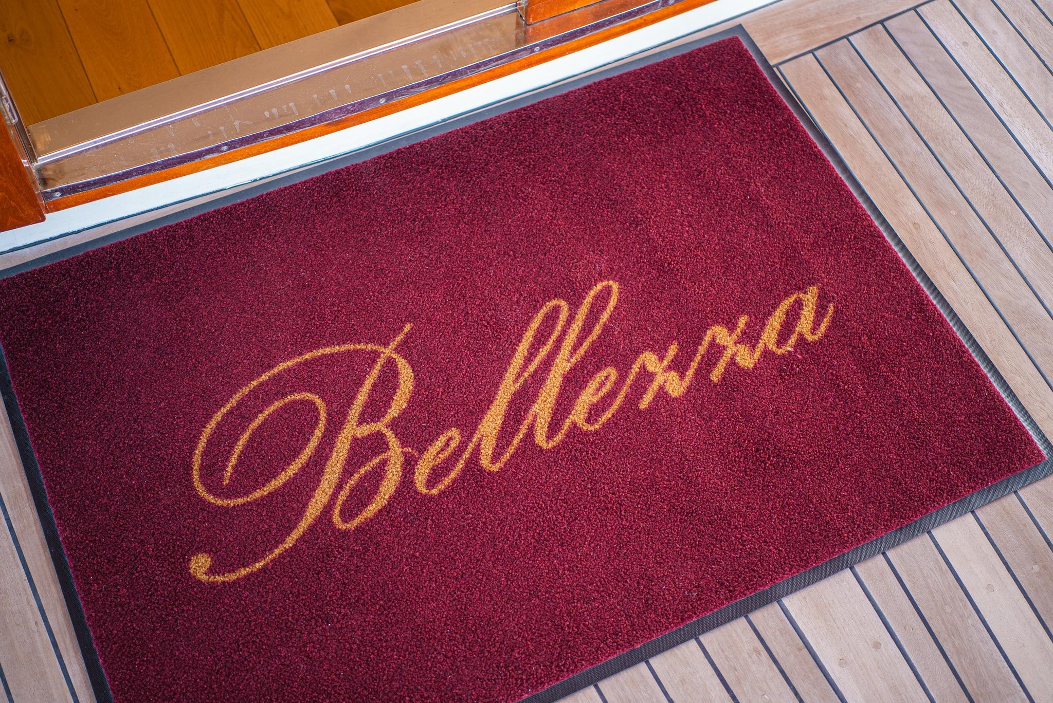 burgundy welcome mat with golden Bellena script lettering on yacht deck