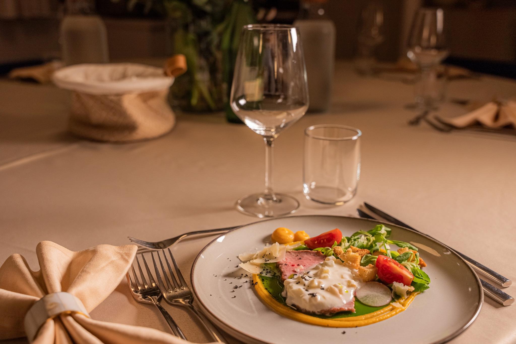 elegant plated salad with wine glass and water glass on yacht dining table