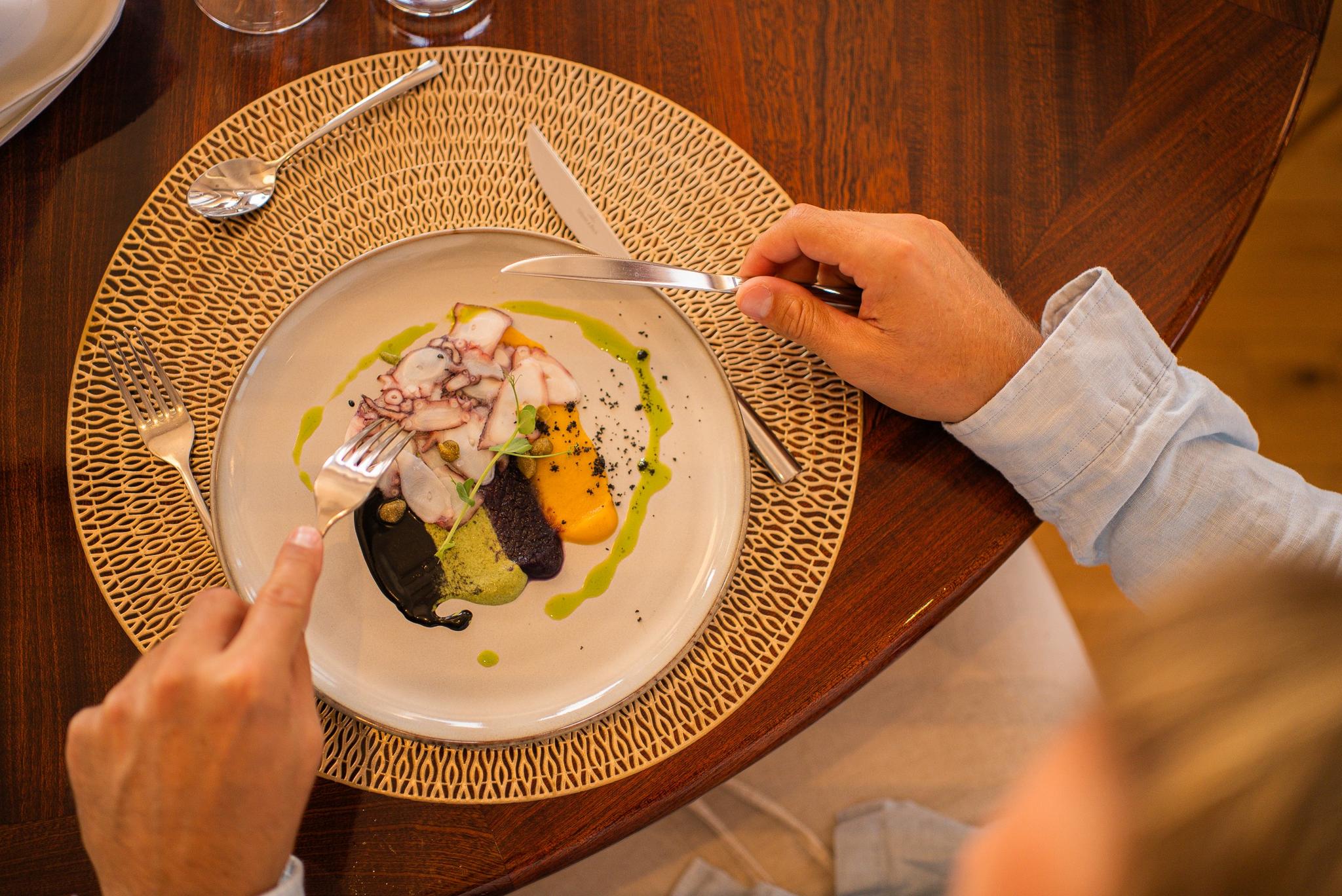 Fine dining scene with plated seafood dish and green sauce being eaten with cutlery