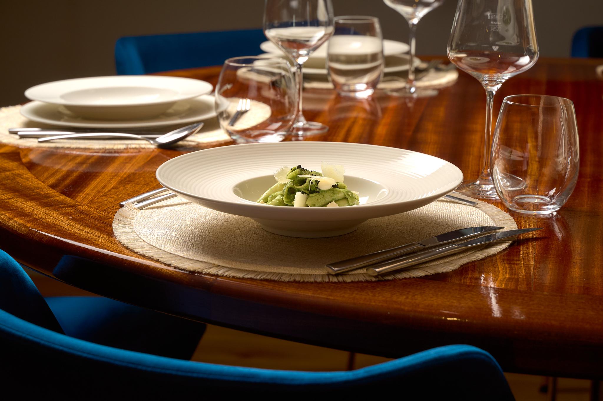 luxury yacht dining table with plated green salad and formal place settings