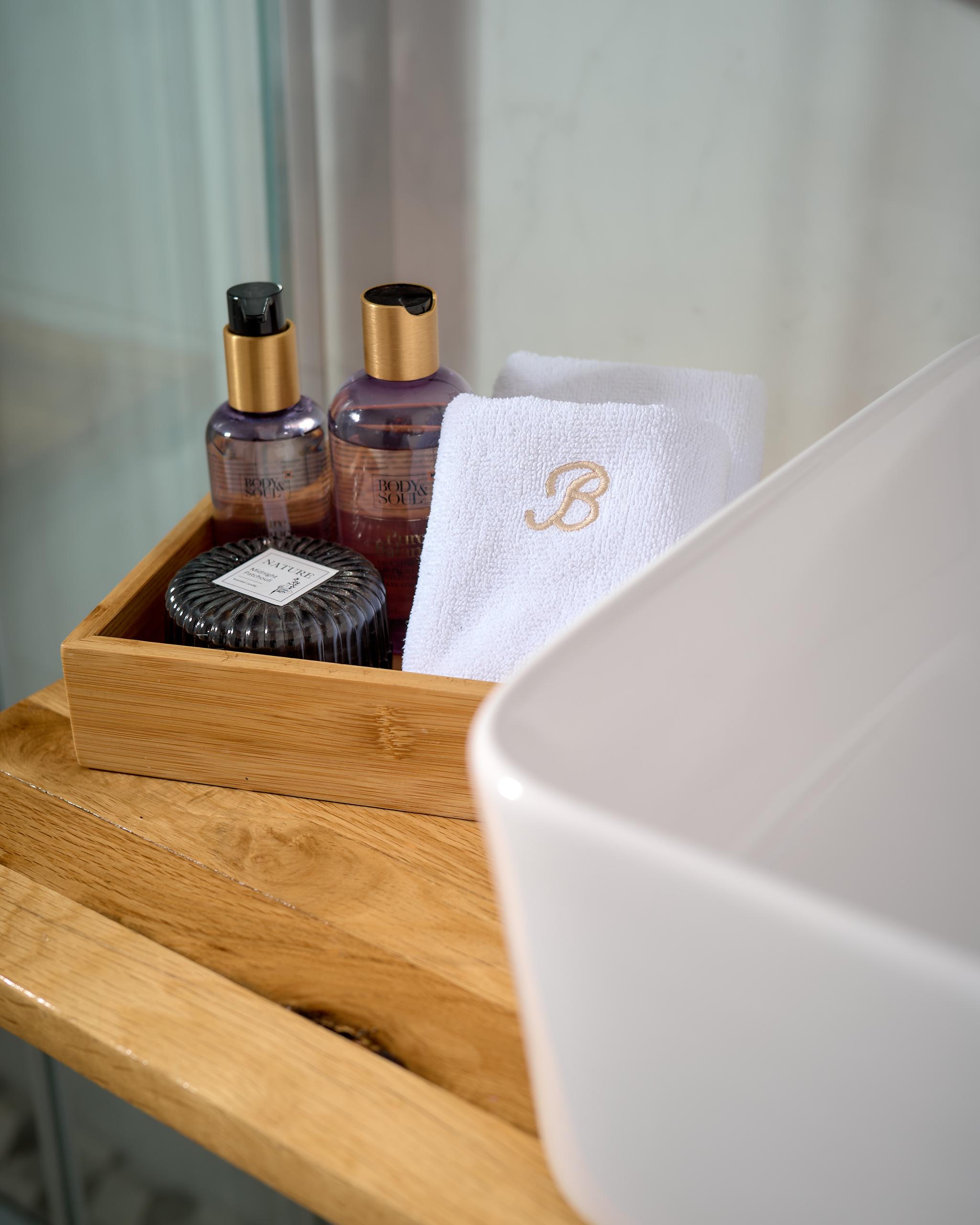 luxury yacht bathroom amenities with Body & Soul toiletries and monogrammed towel in bamboo tray