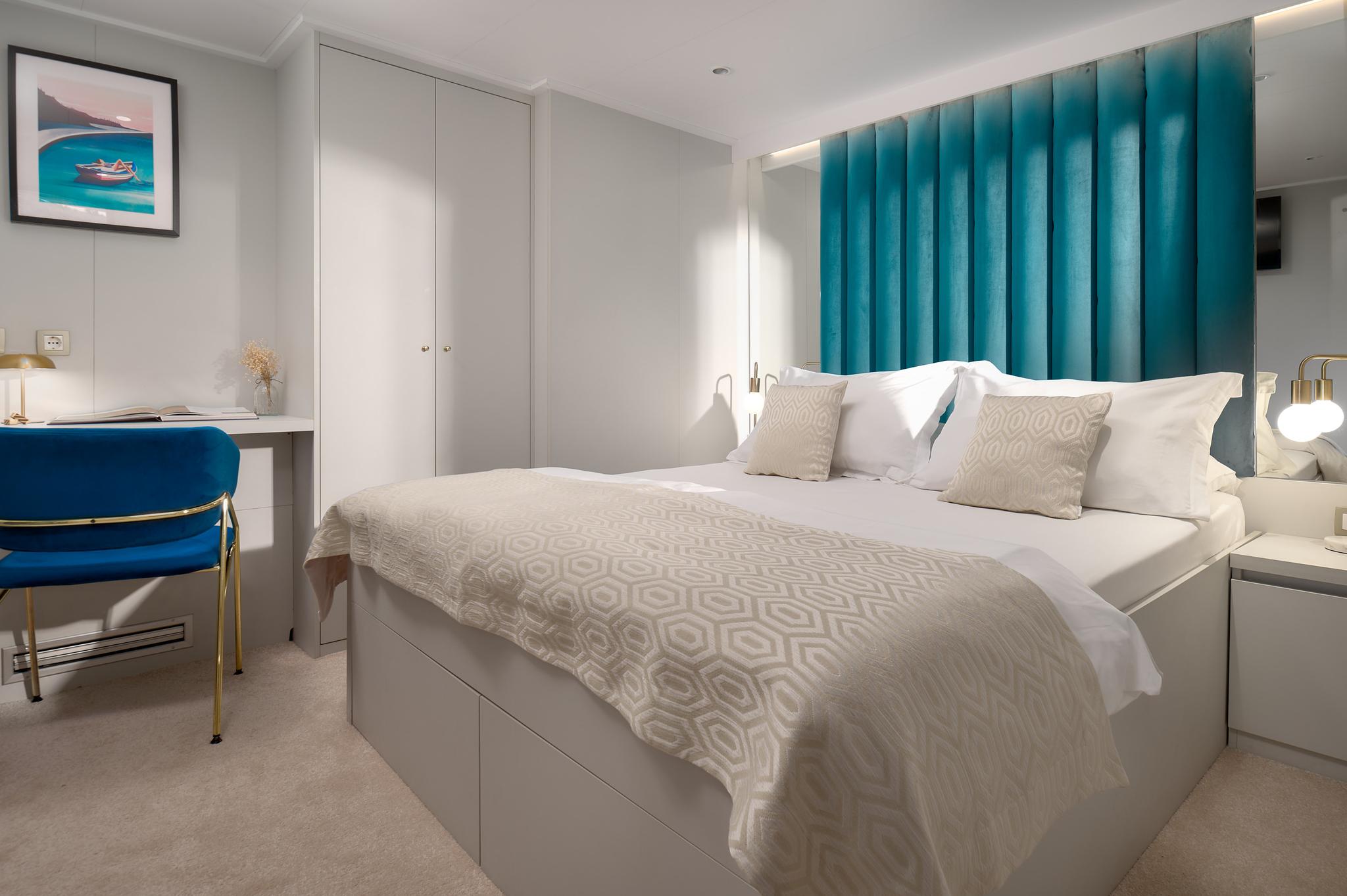 yacht guest cabin featuring double bed with geometric bedding and built-in desk