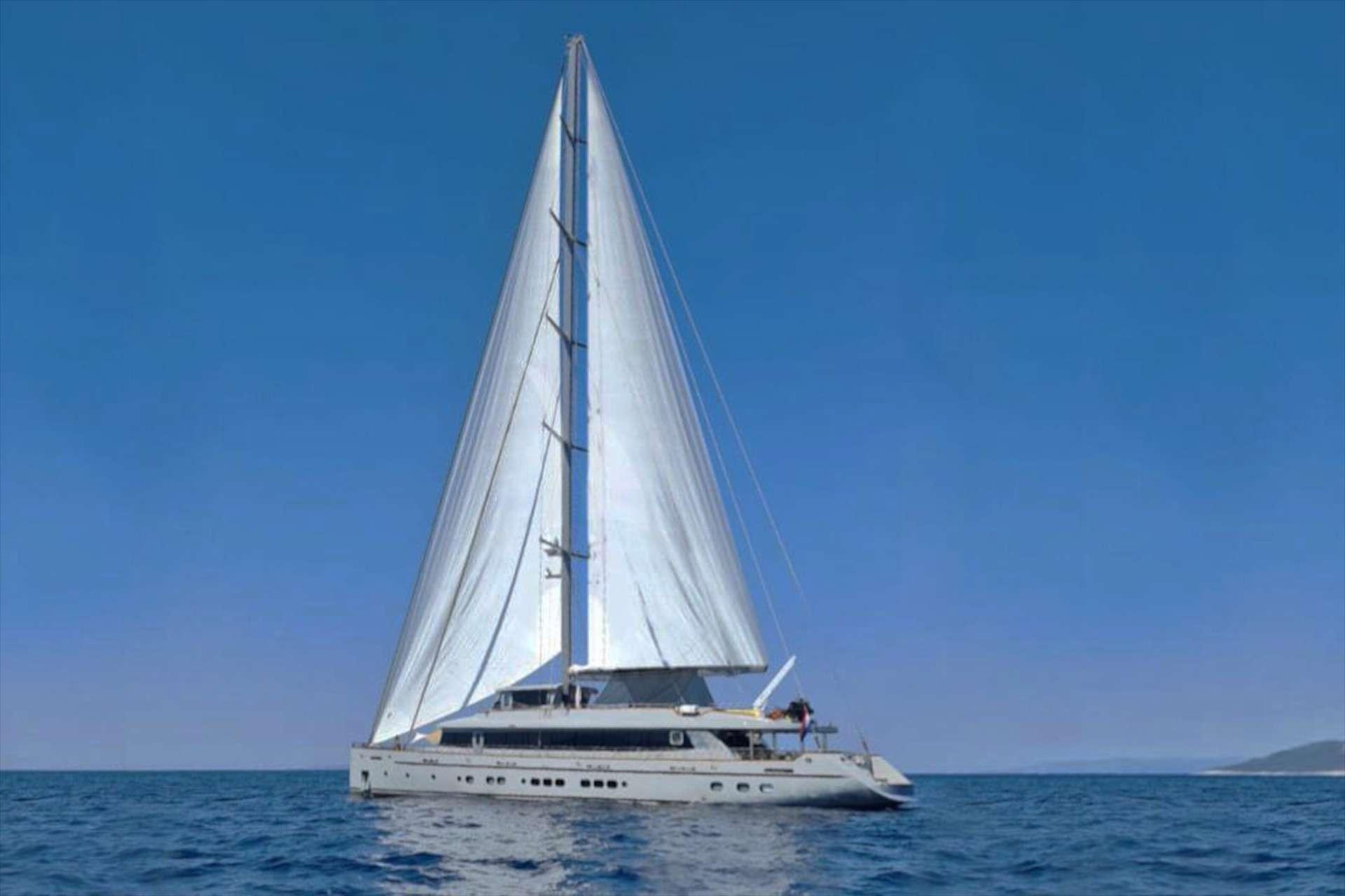 Large luxury sailing gulet underway with full white mainsail raised against clear blue sky