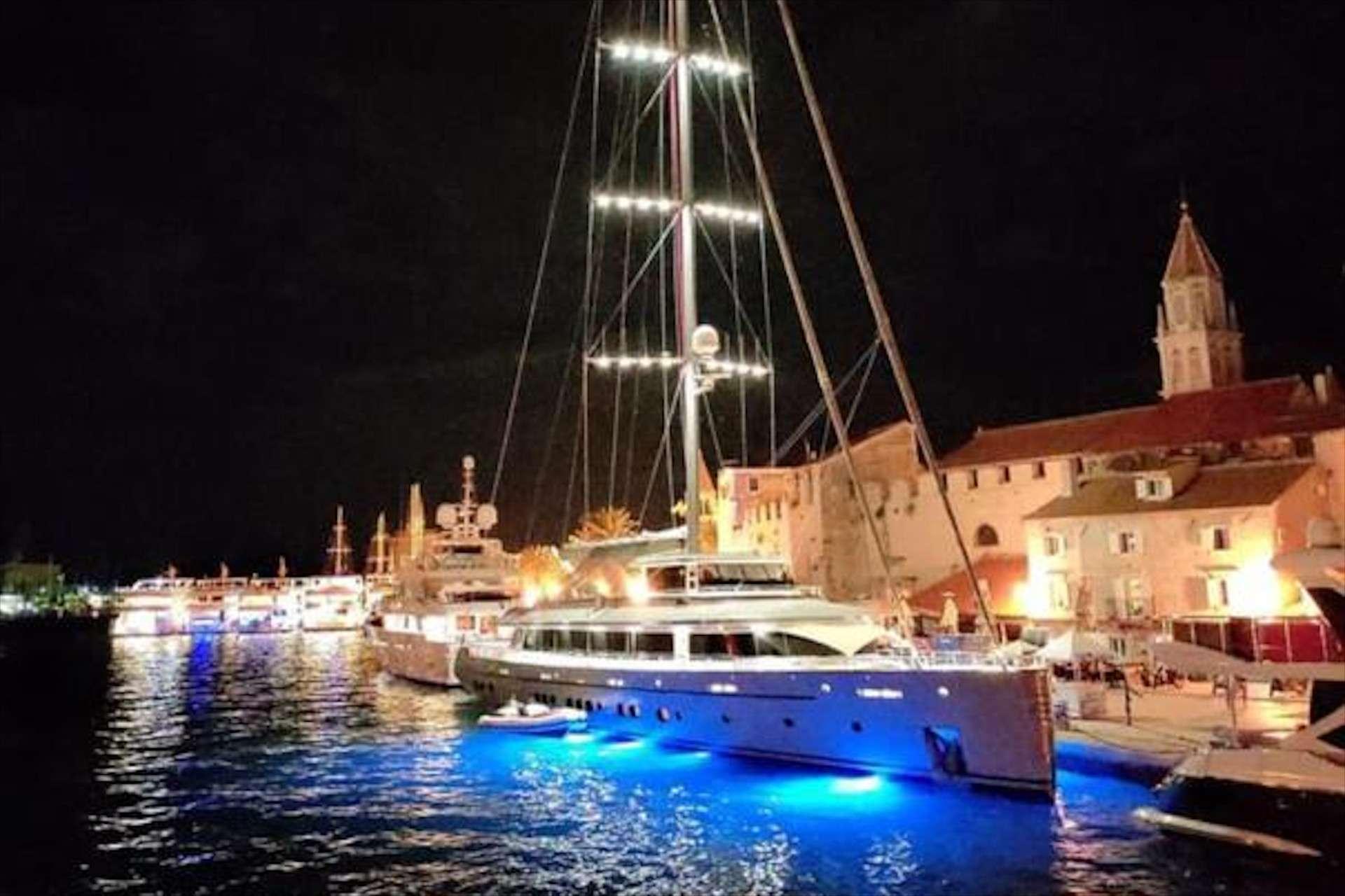 luxury motor yacht docked at night with vivid blue underwater hull lighting in Trogir Croatia