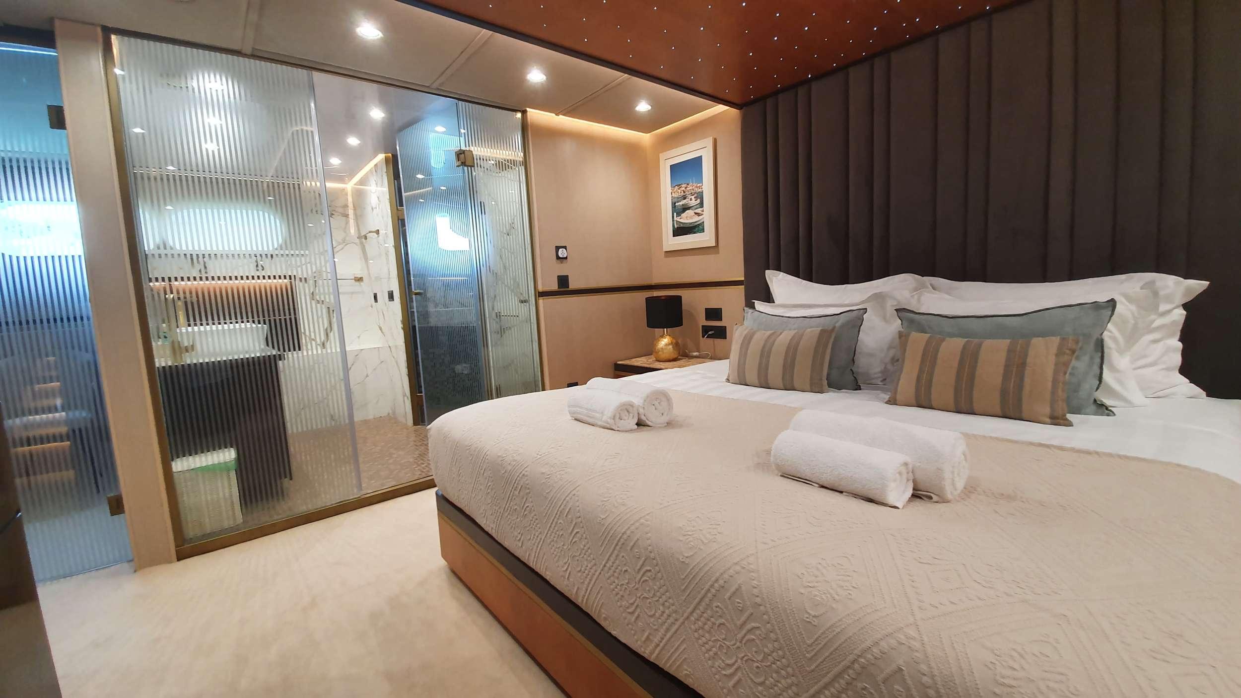 Luxury master cabin with king bed, star-ceiling, and glass-partitioned marble ensuite shower room