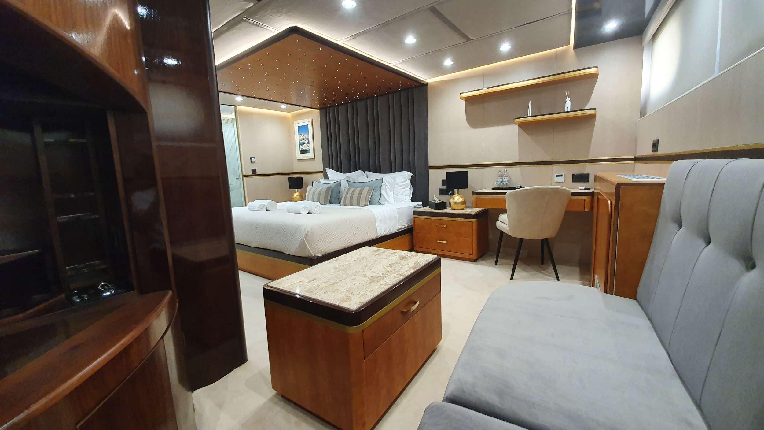 Luxury master cabin featuring king bed with star-light canopy, marble-top ottoman, writing desk and seating area