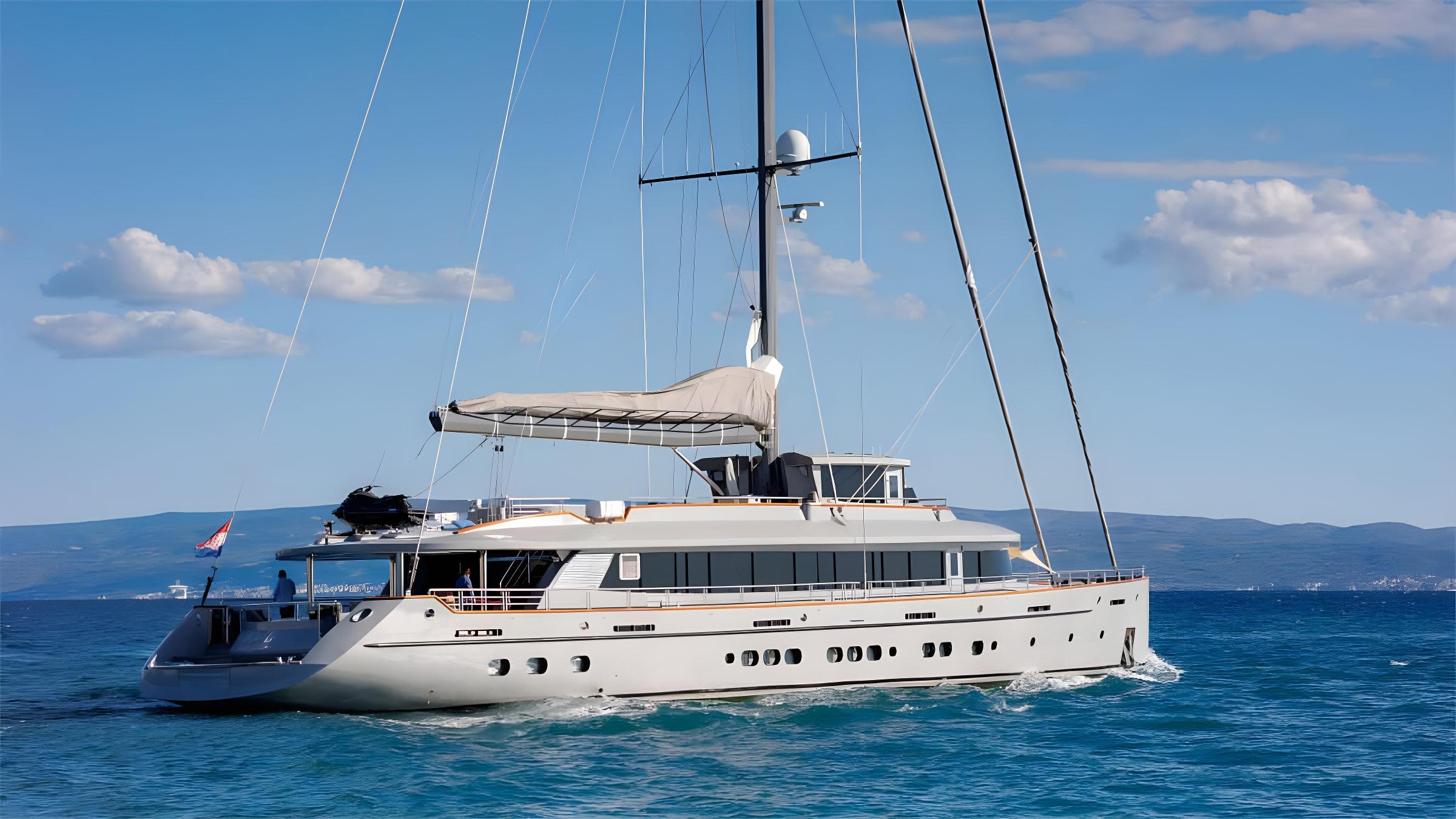 Large luxury sailing gulet underway on blue sea with furled mainsail and Croatian coastline behind