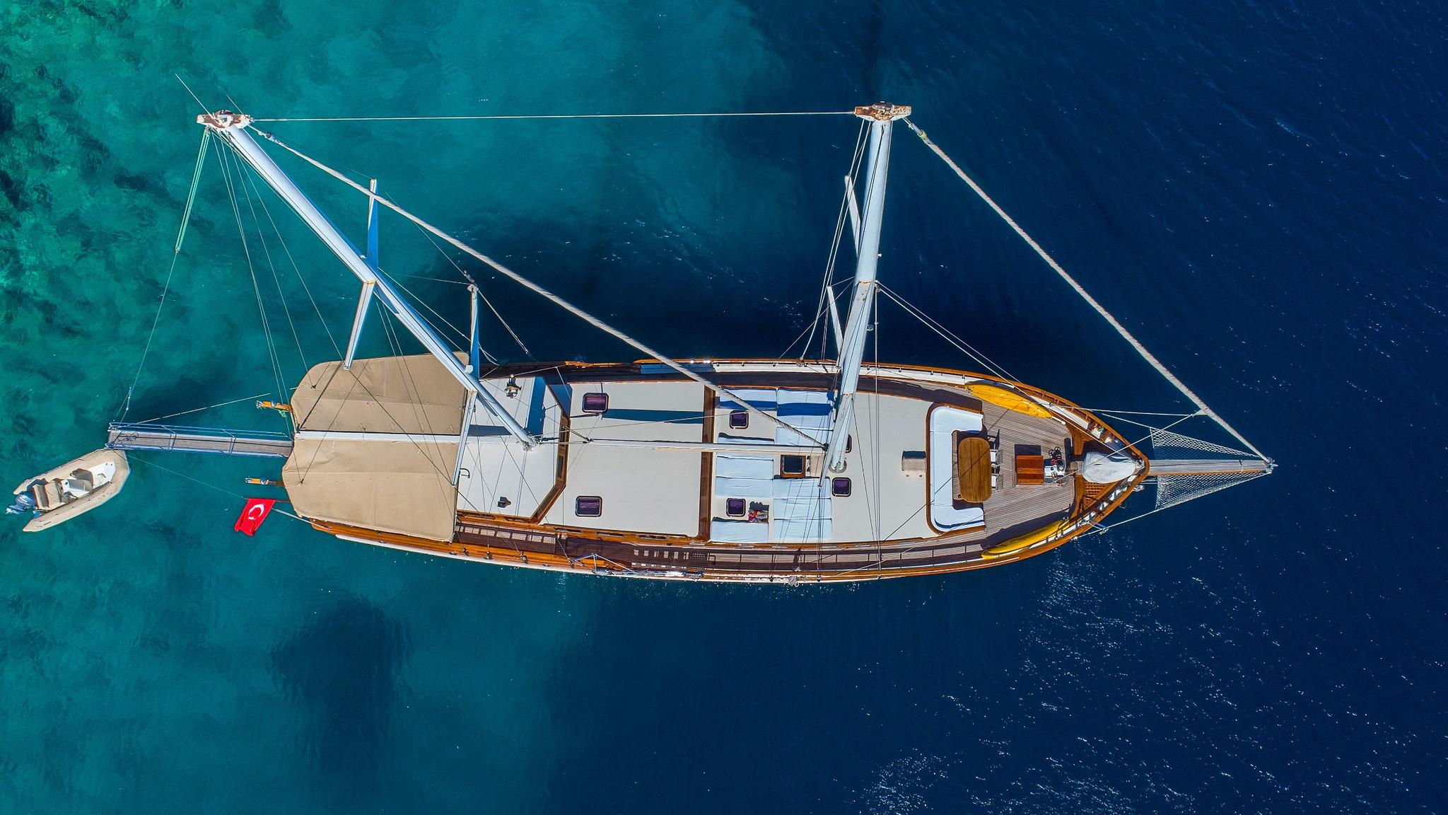 aerial view of traditional wooden gulet yacht with white hull anchored in crystal clear turquoise waters