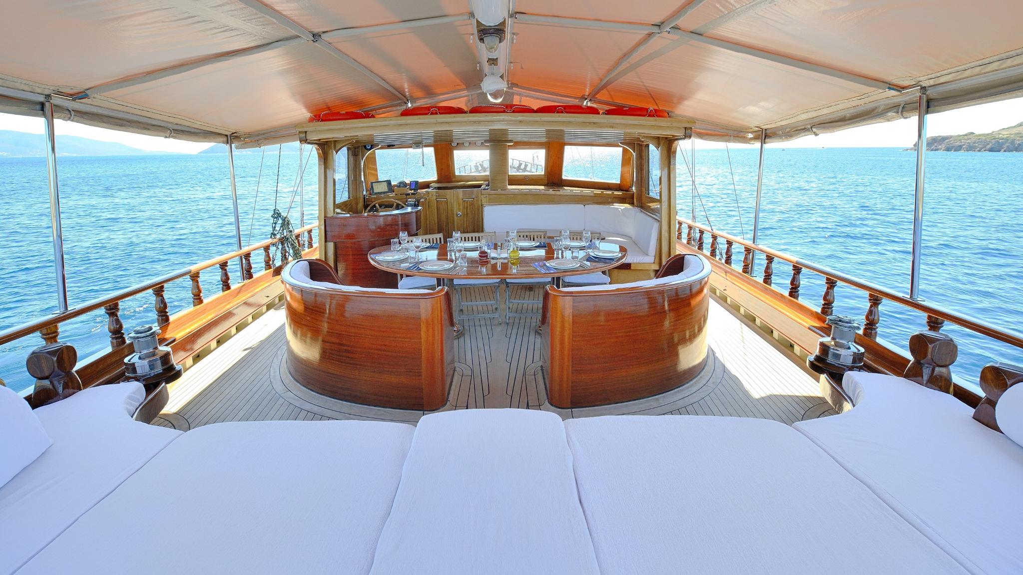 circular jacuzzi with curved wooden bench seating on yacht deck under canvas awning