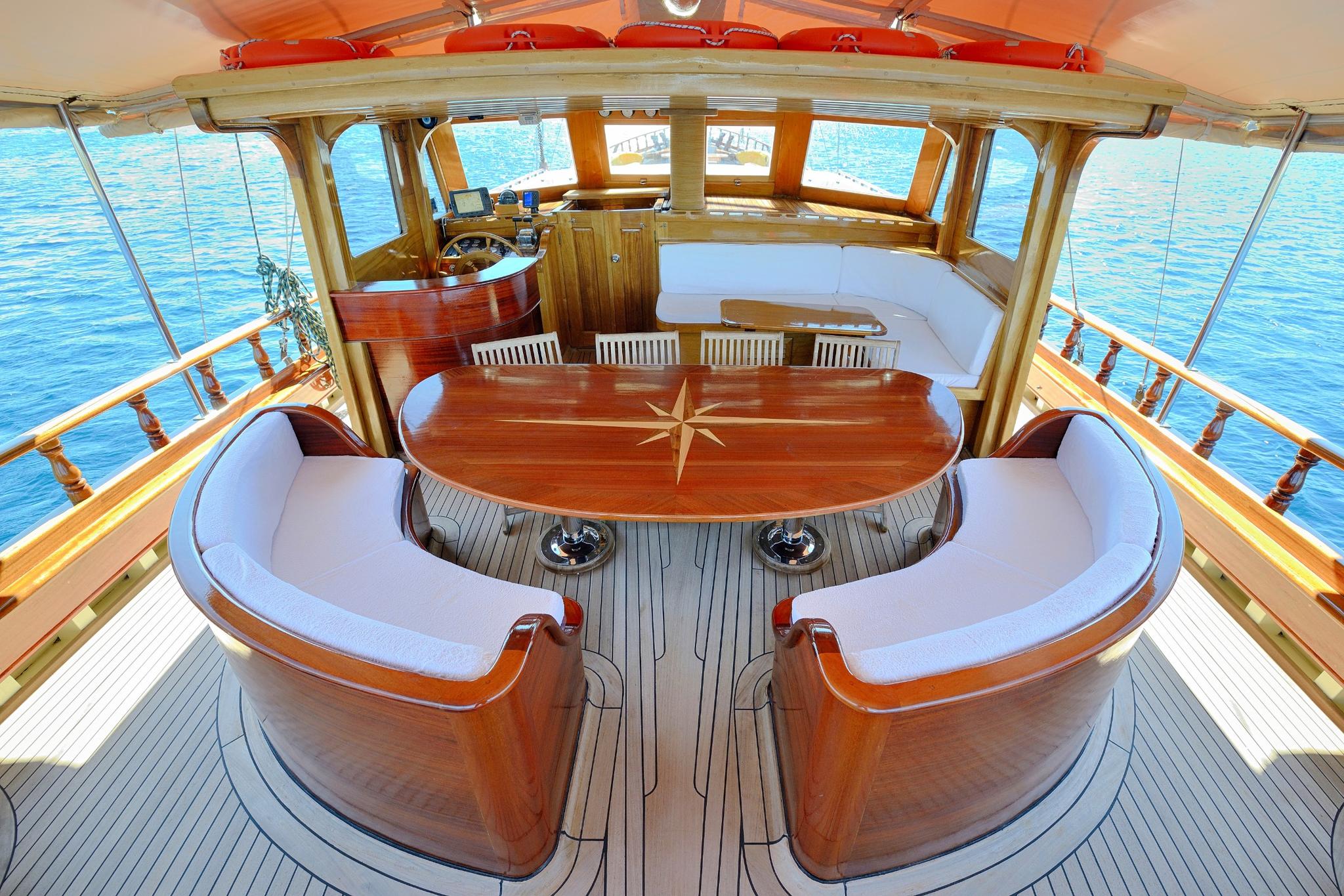 luxury gulet covered aft deck with curved banquette seating around oval dining table