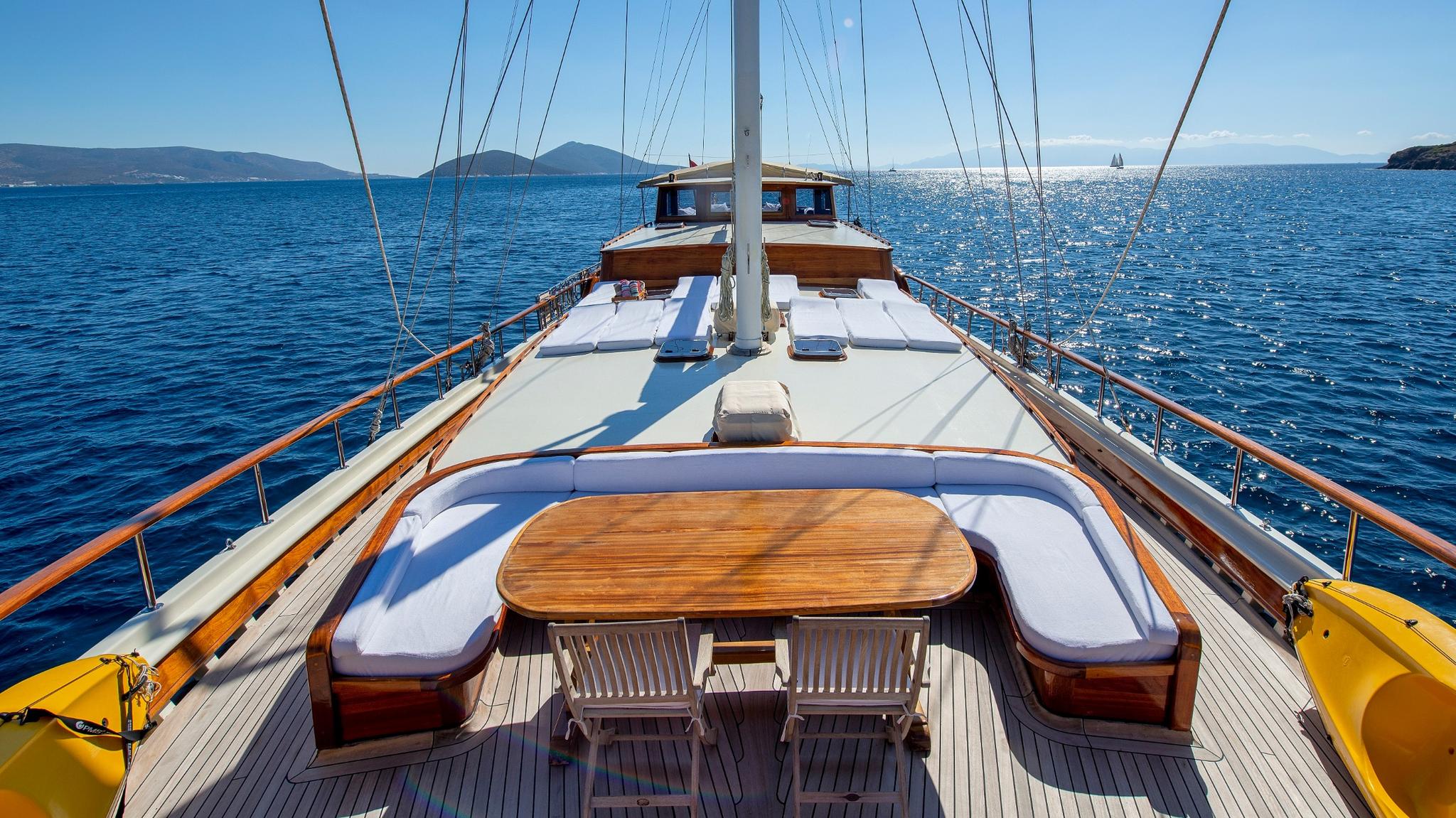 gulet foredeck with curved banquette seating around oval teak dining table