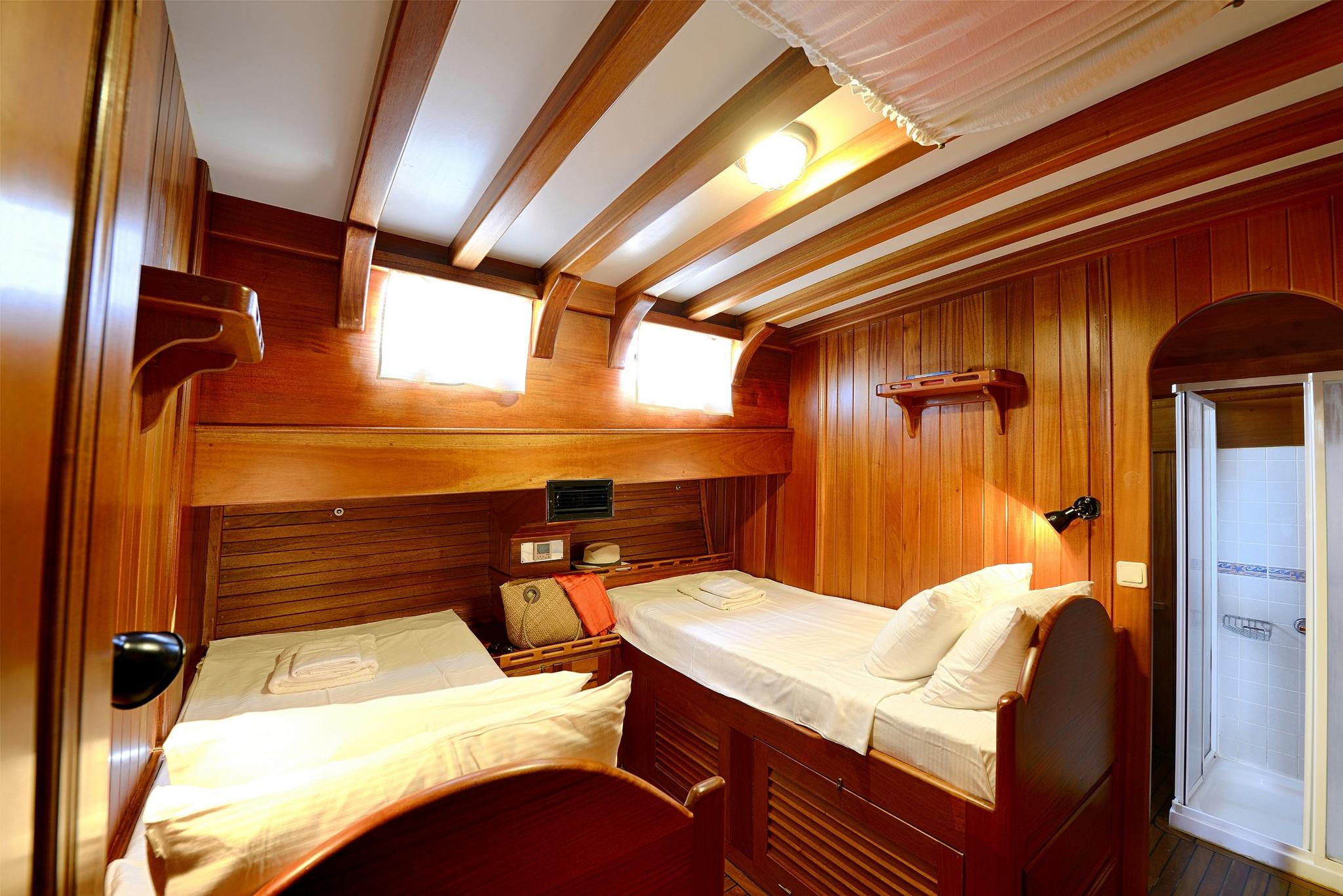 twin cabin interior with two single beds, rich wood paneling and exposed ceiling beams
