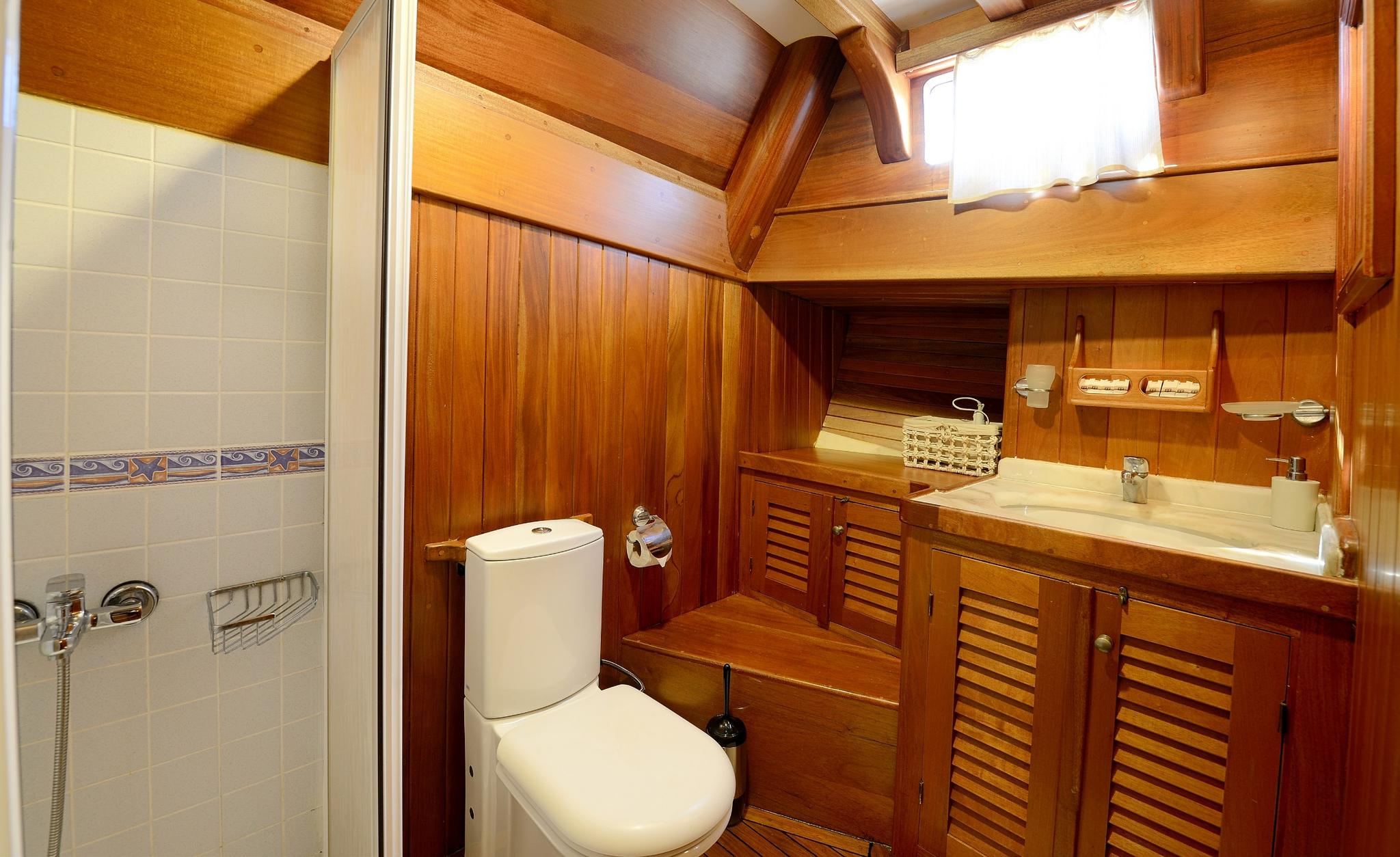 yacht bathroom featuring tiled shower, white toilet, wooden vanity with sink and mirror