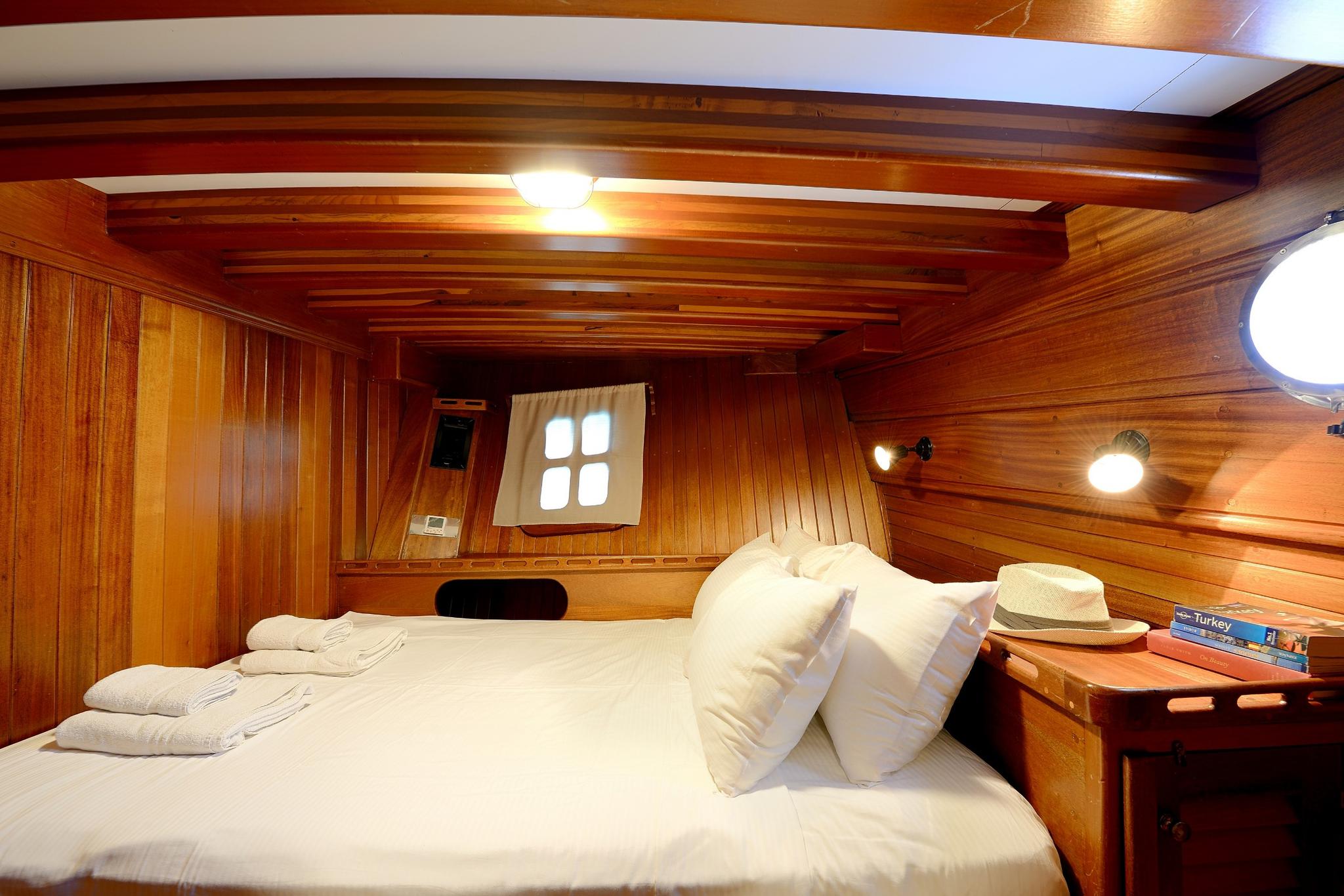 yacht guest cabin featuring double bed with white linens and traditional wood paneling