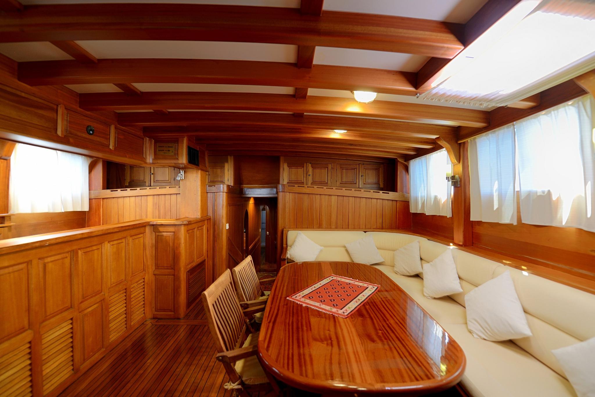 yacht interior salon with oval dining table, built-in seating and traditional wood paneling