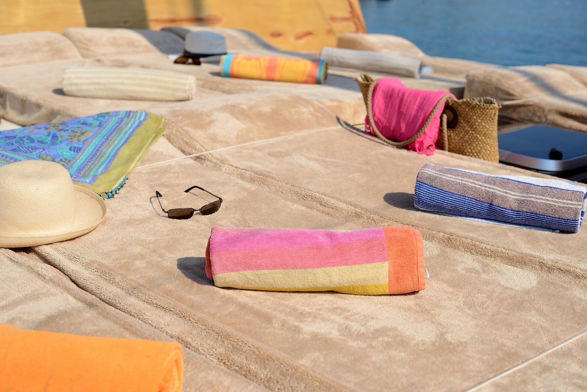 yacht sun deck with beige cushioned loungers, colorful towels, sunglasses and beach accessories