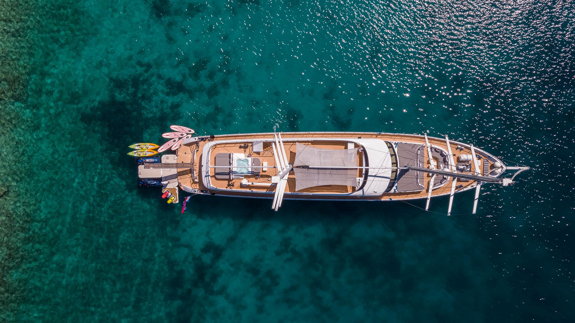 aerial view of luxury gulet yacht with teak decks anchored in crystal clear turquoise bay