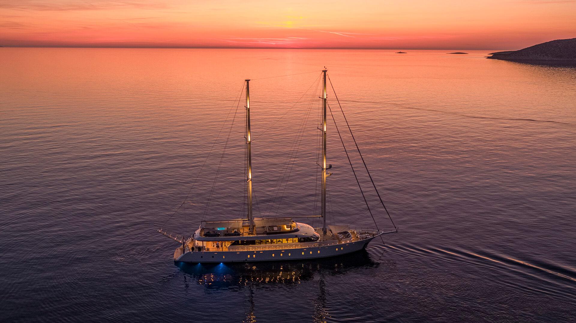 aerial view luxury sailing yacht anchored at sunset with deck lighting and underwater illumination
