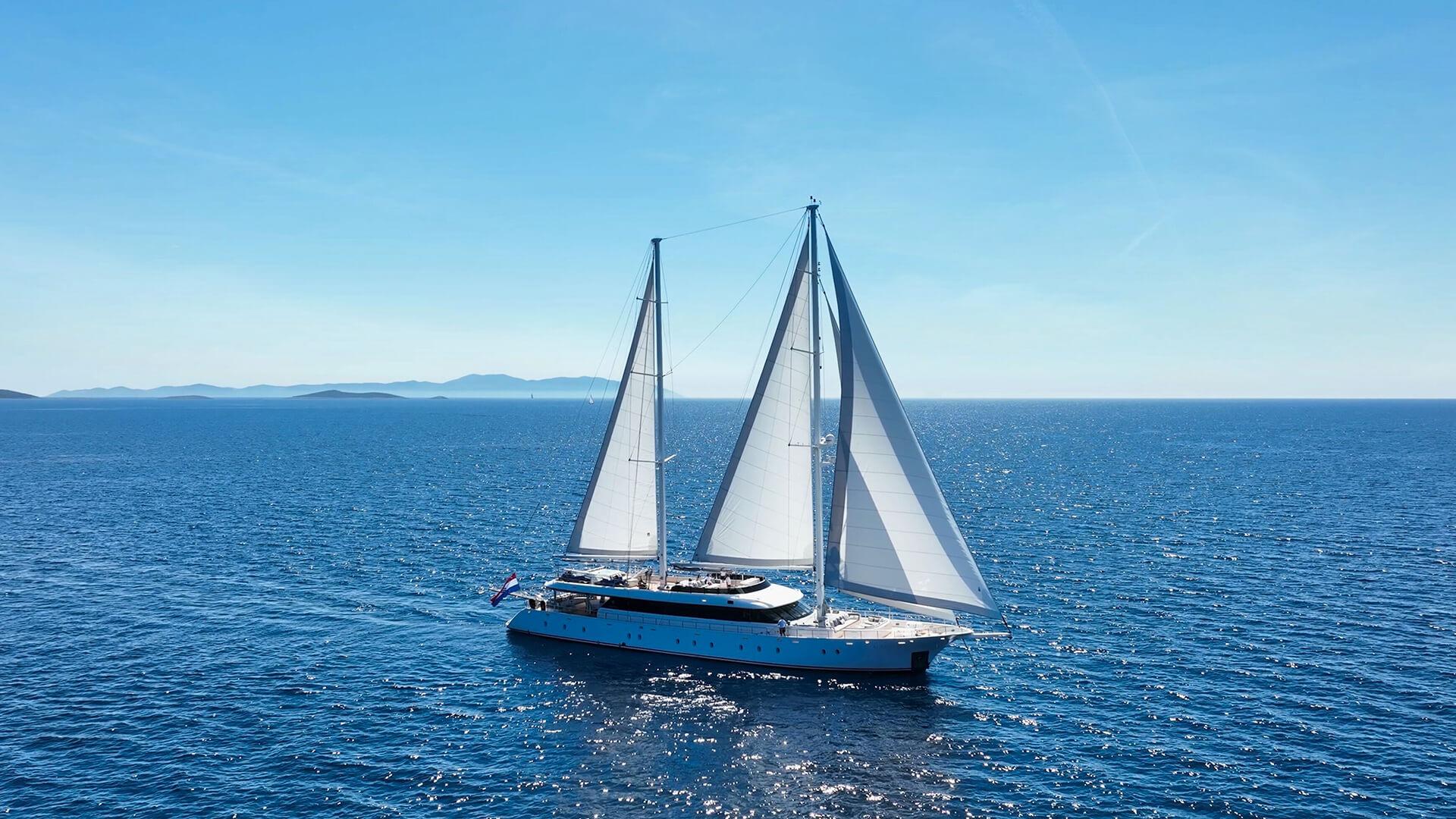 luxury sailing yacht with white sails deployed cruising on calm blue Mediterranean waters