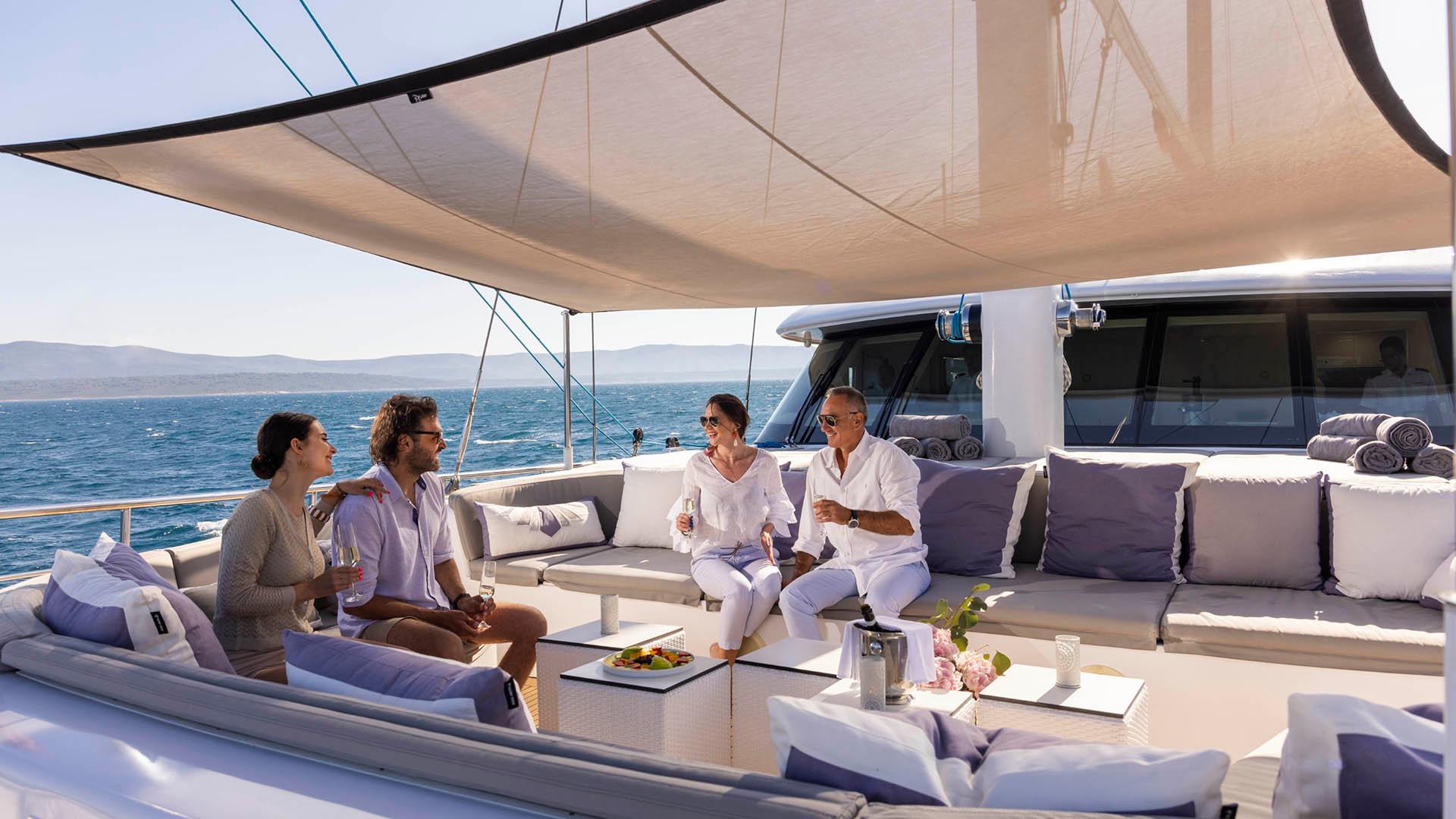 yacht aft deck lounge with L-shaped seating, coffee table, and guests enjoying drinks