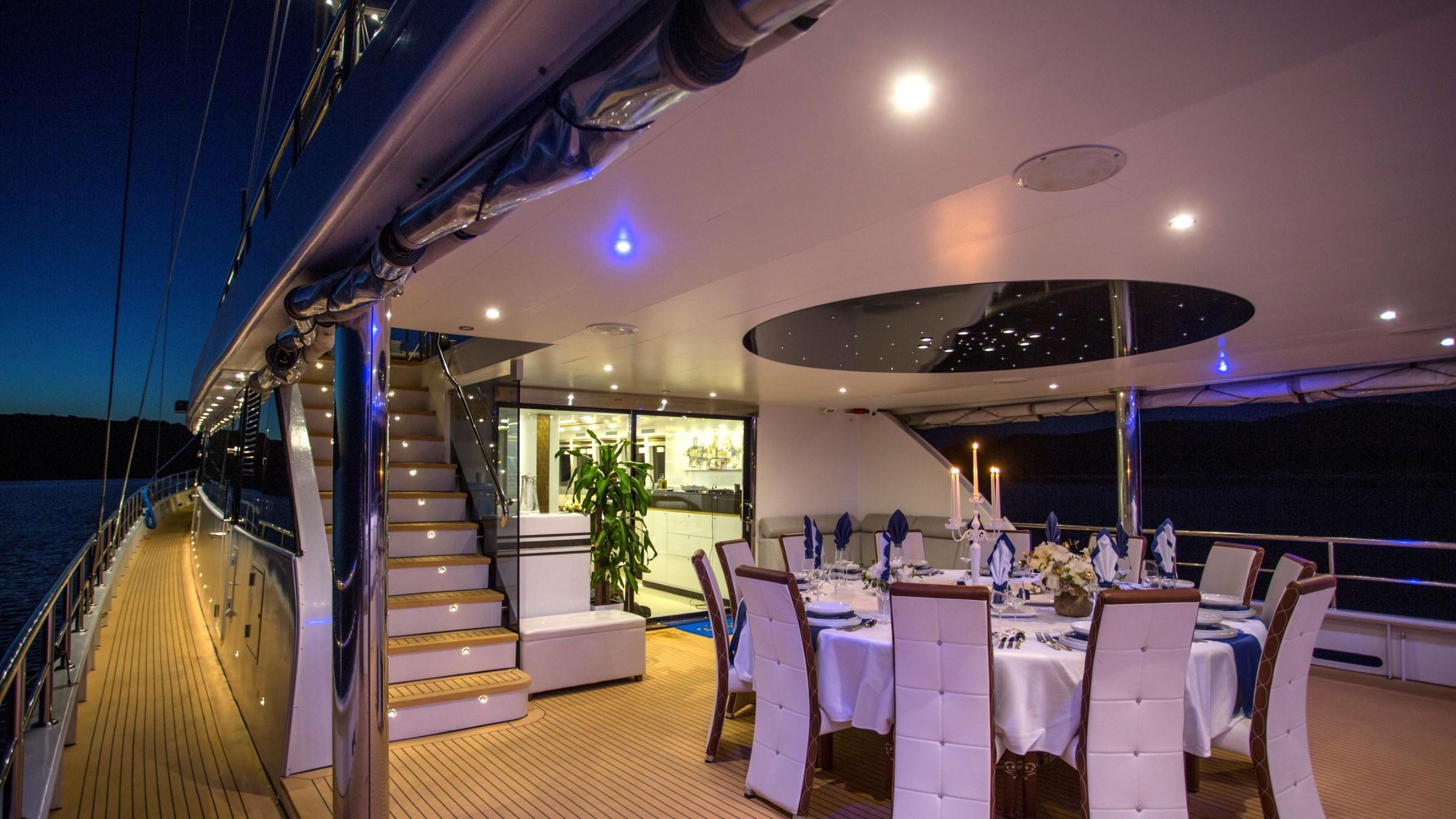 luxury yacht aft deck dining area with formal table setting at night