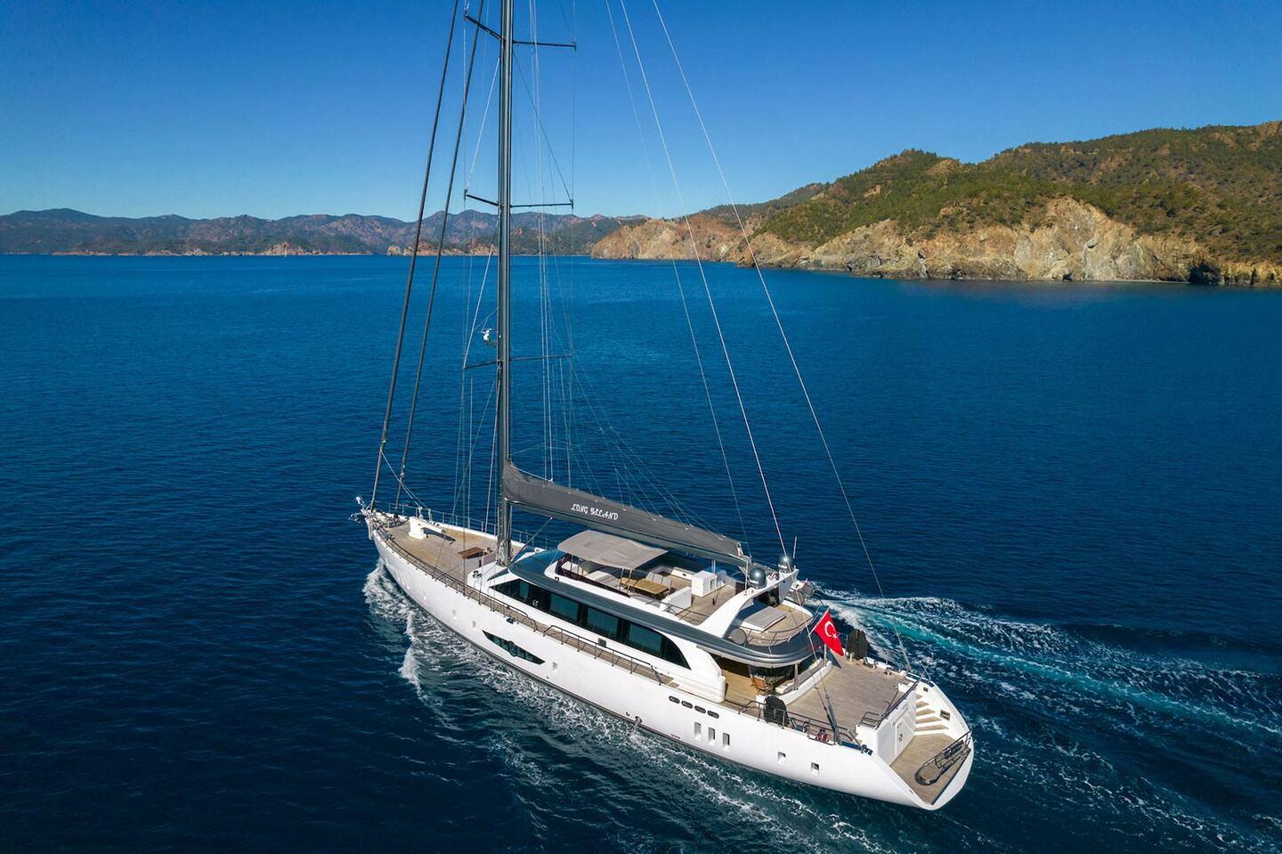 aerial view of white sailing yacht underway with wake trail in blue Mediterranean waters