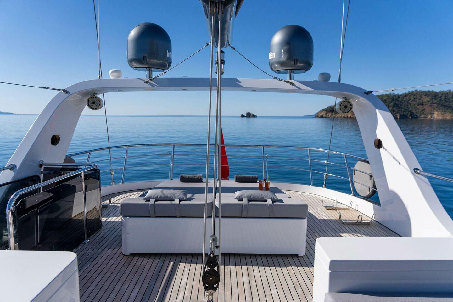 bow deck with white cushioned seating benches and stainless steel railings overlooking calm blue waters