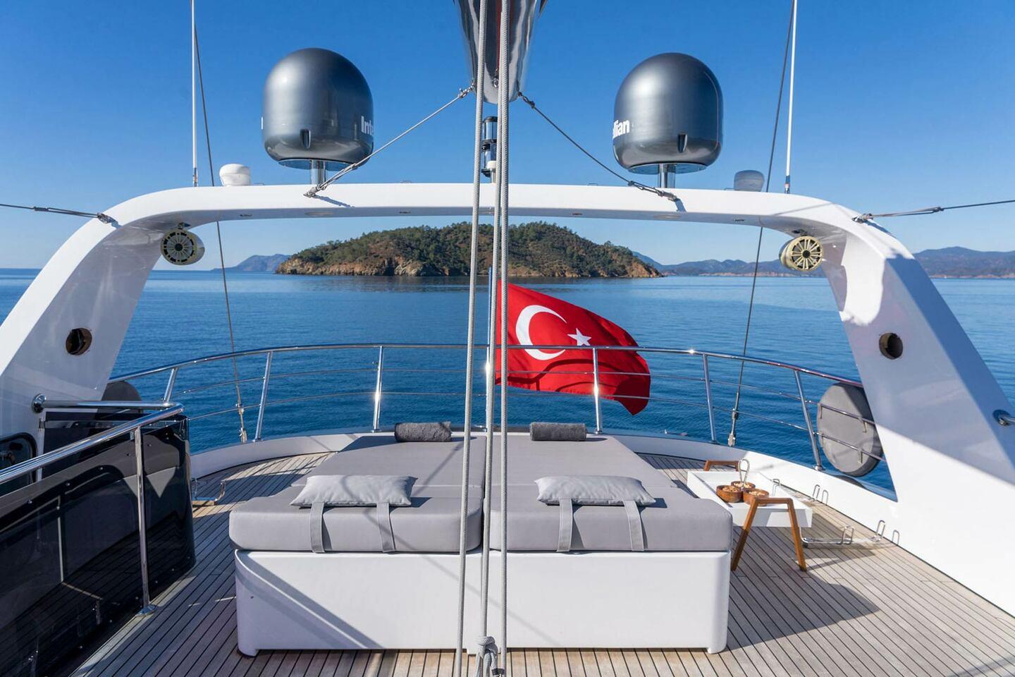 yacht aft deck with white cushioned seating area and Turkish flag flying