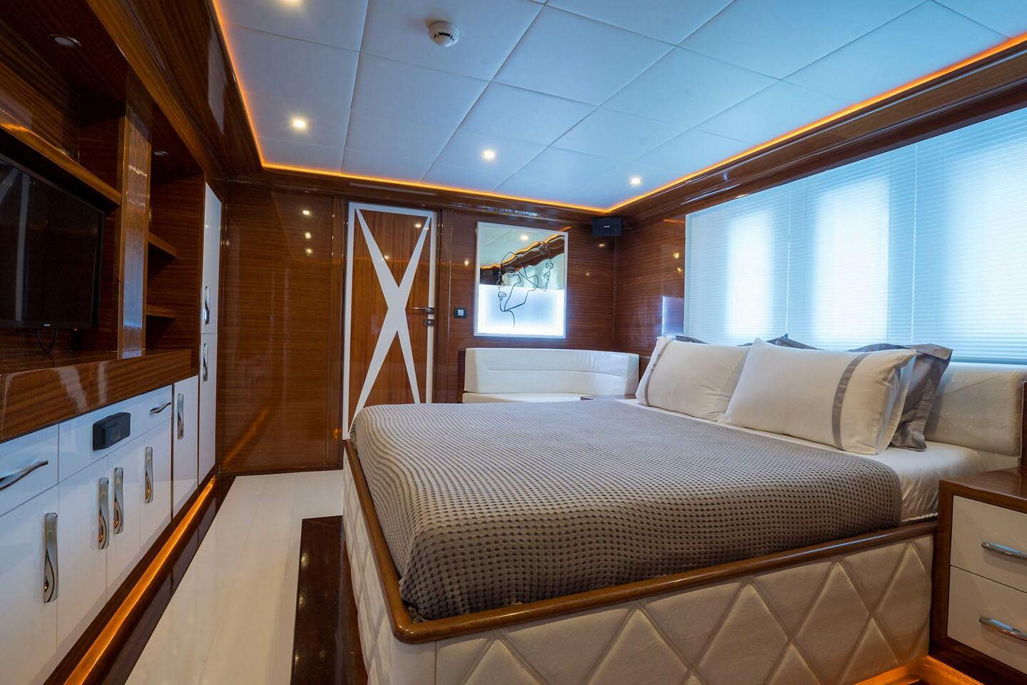 luxury yacht cabin featuring double bed with gray bedding and rich wooden paneling