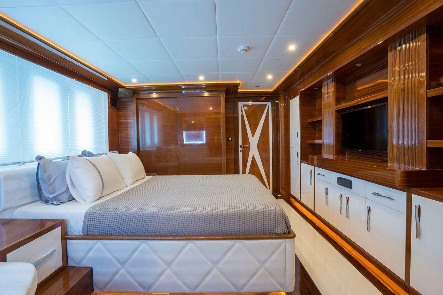 Master cabin with king size bed, white quilted base, built-in entertainment center and panoramic windows