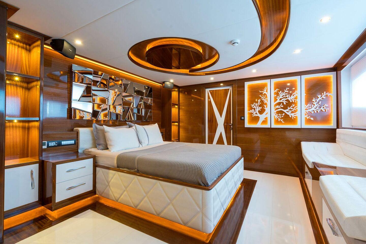 luxury yacht master cabin featuring king bed with quilted base, curved wood ceiling with ambient lighting