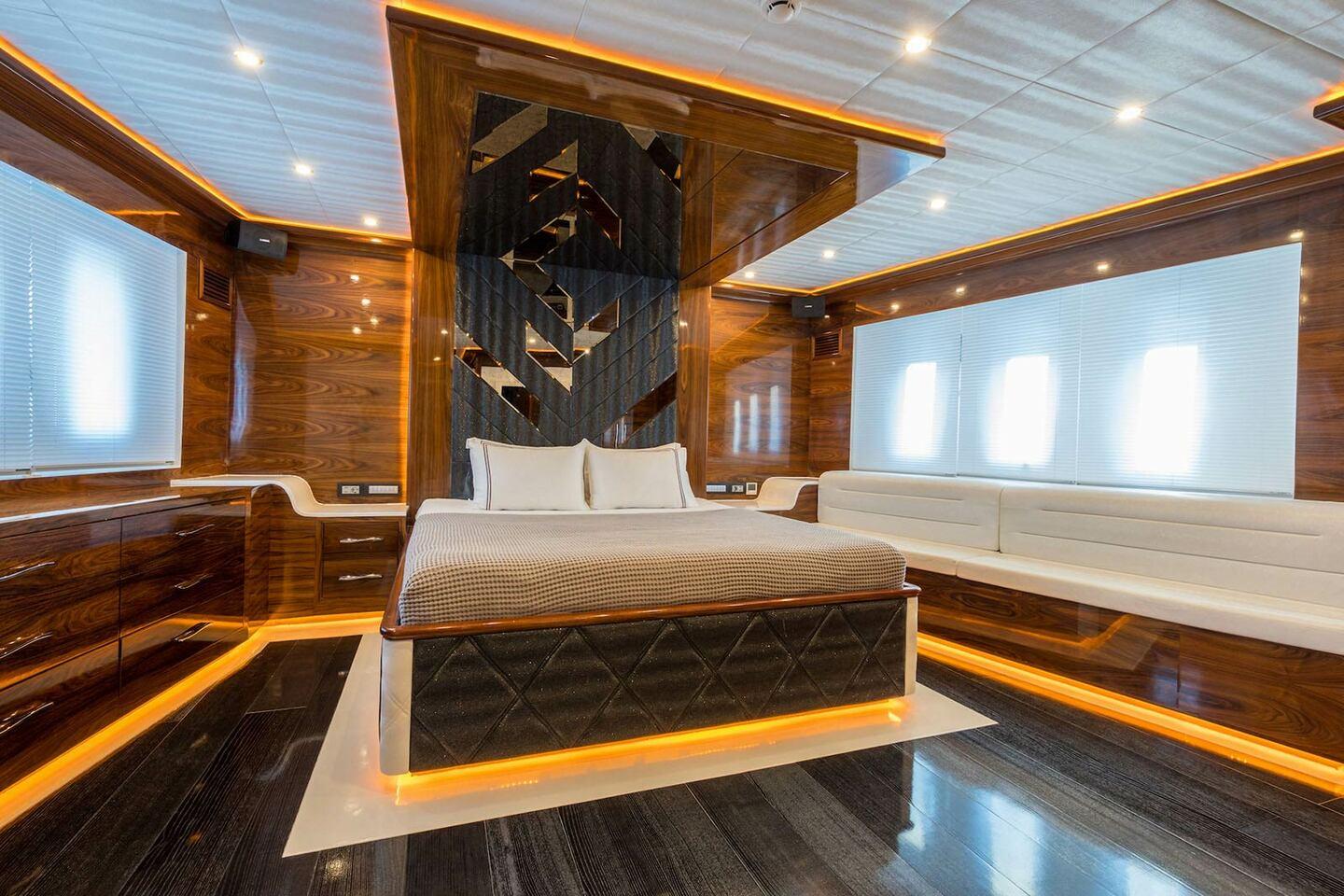 luxury yacht master cabin featuring king bed with geometric headboard and white seating area