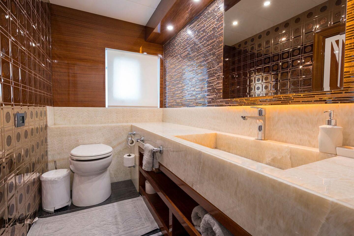 Yacht bathroom featuring cream marble vanity, geometric wall tiles, toilet and bidet