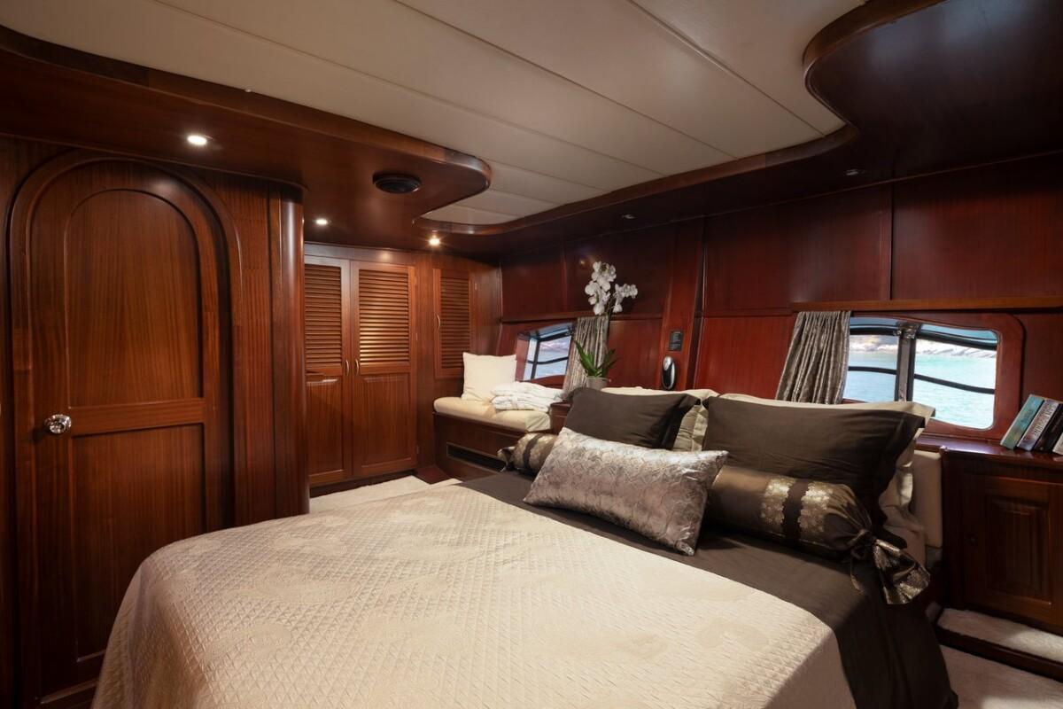 luxury yacht master cabin featuring king size bed with decorative pillows and rich mahogany woodwork