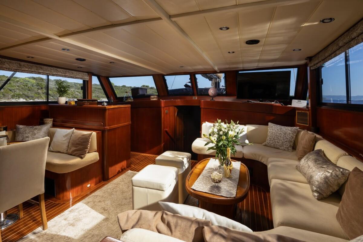 yacht main salon with curved cream sofas, oval coffee table, and panoramic windows