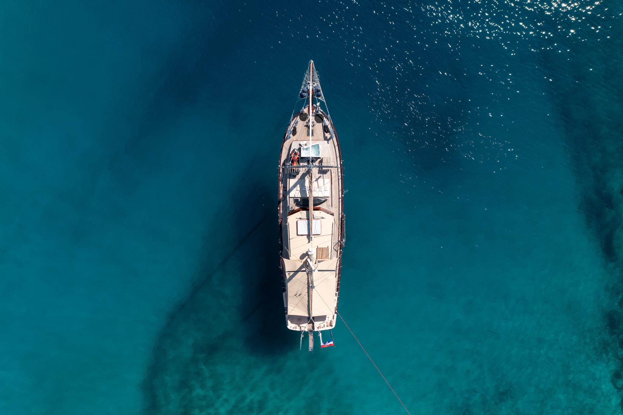 aerial view of traditional gulet yacht at anchor in crystal clear turquoise Mediterranean waters