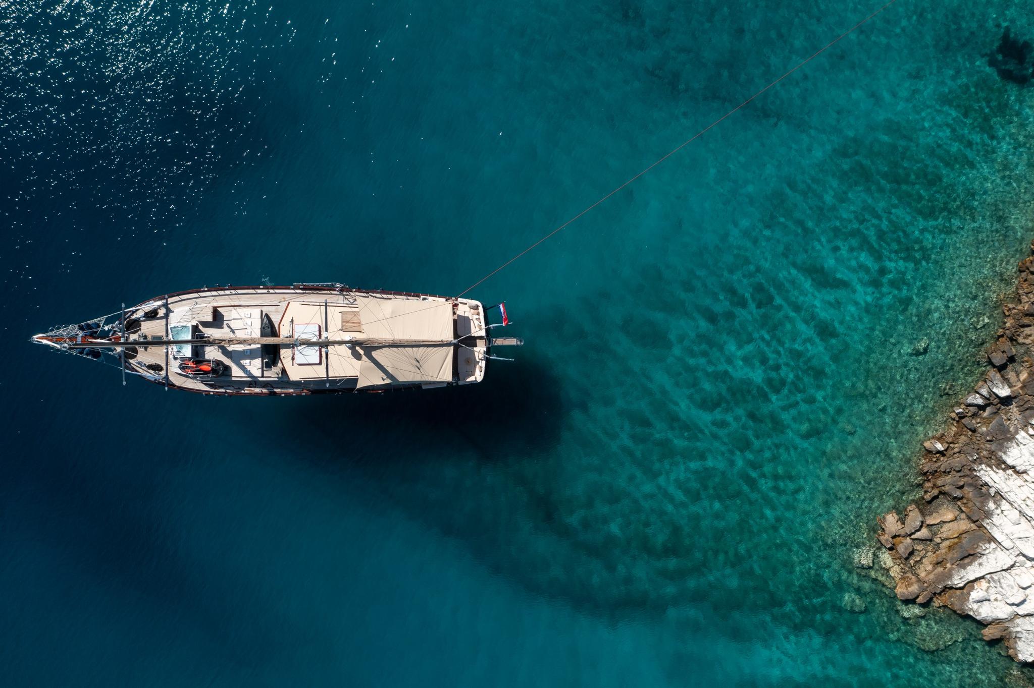 aerial view of traditional wooden gulet yacht anchored in crystal clear turquoise Mediterranean waters