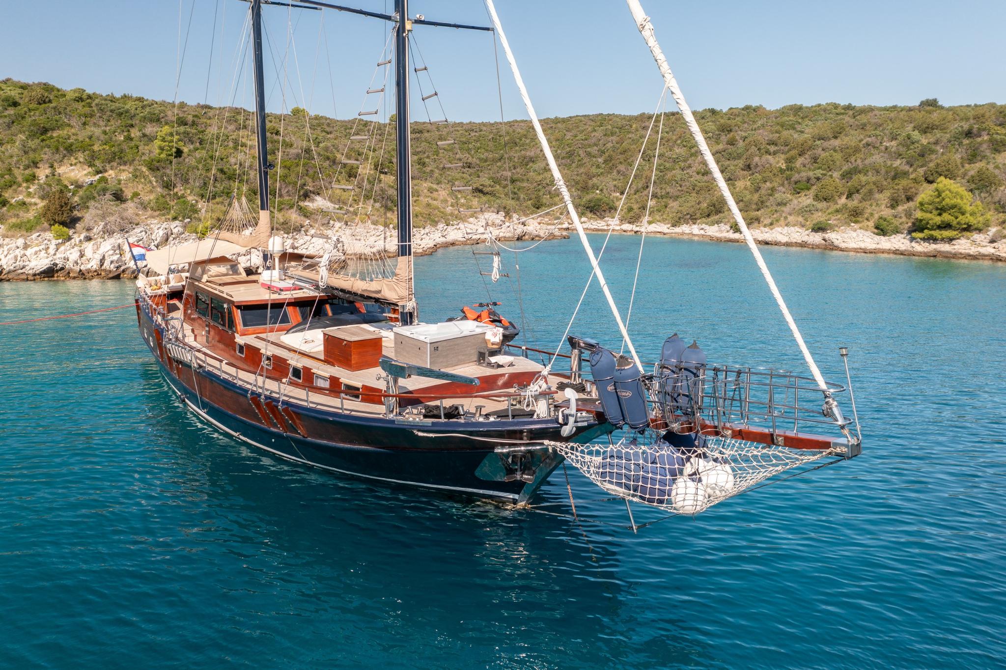 traditional wooden gulet yacht with rope mesh swimming platform at bow in turquoise bay