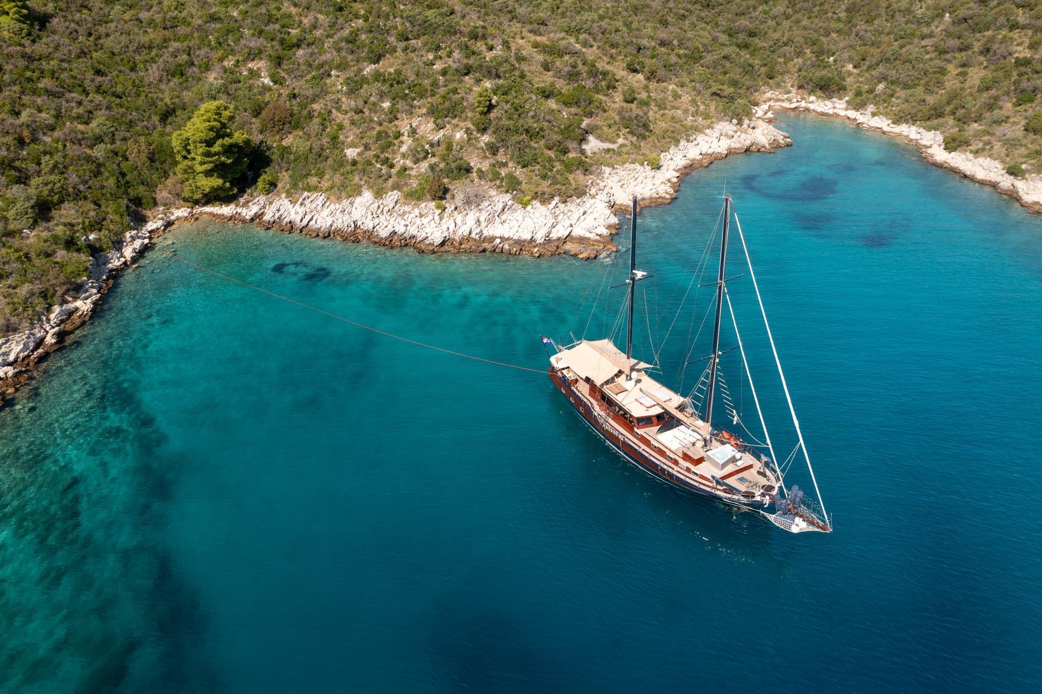 aerial view of traditional wooden gulet yacht anchored in crystal clear turquoise bay