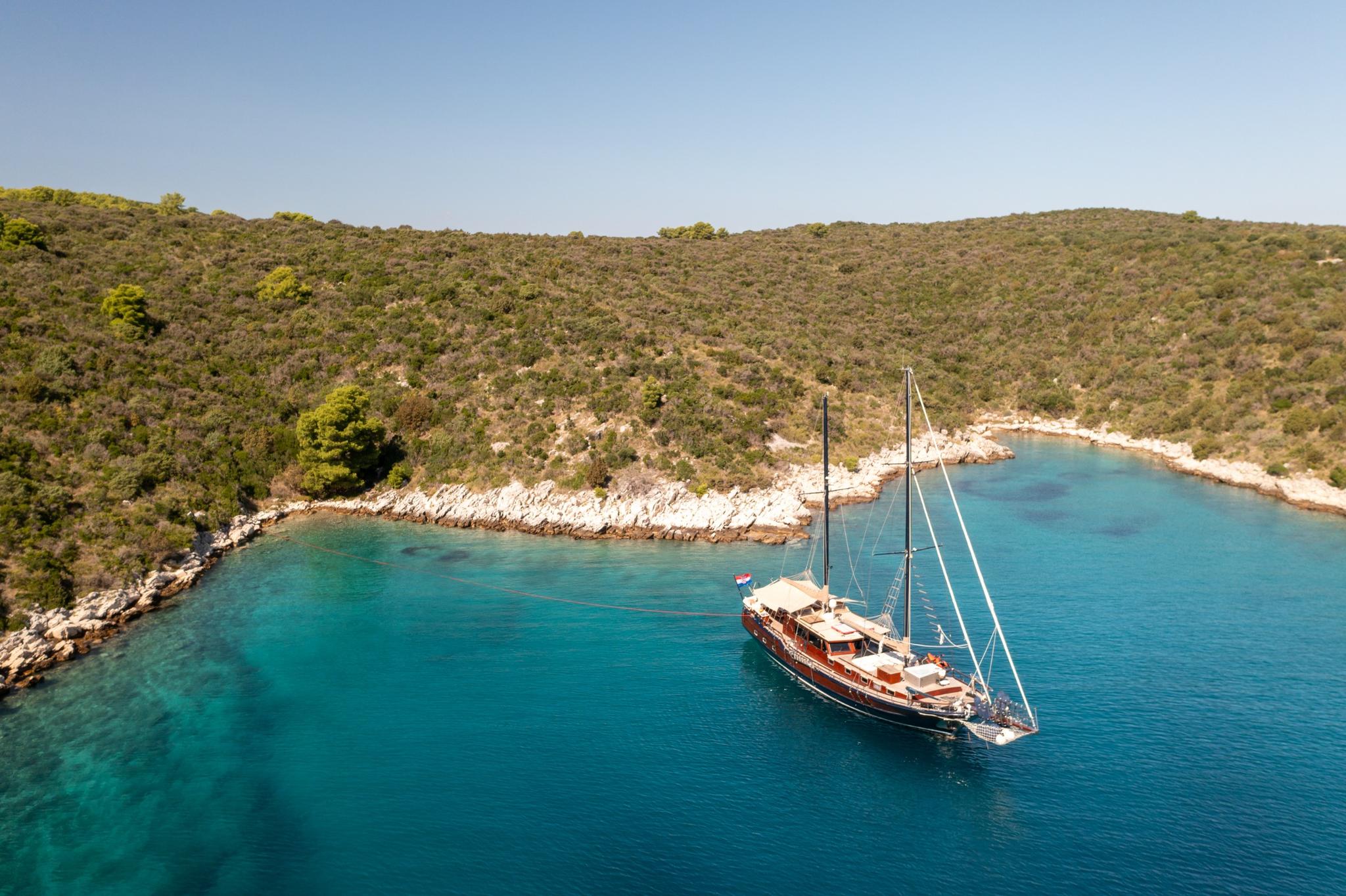 aerial view of traditional wooden gulet yacht anchored in crystal clear turquoise Mediterranean bay