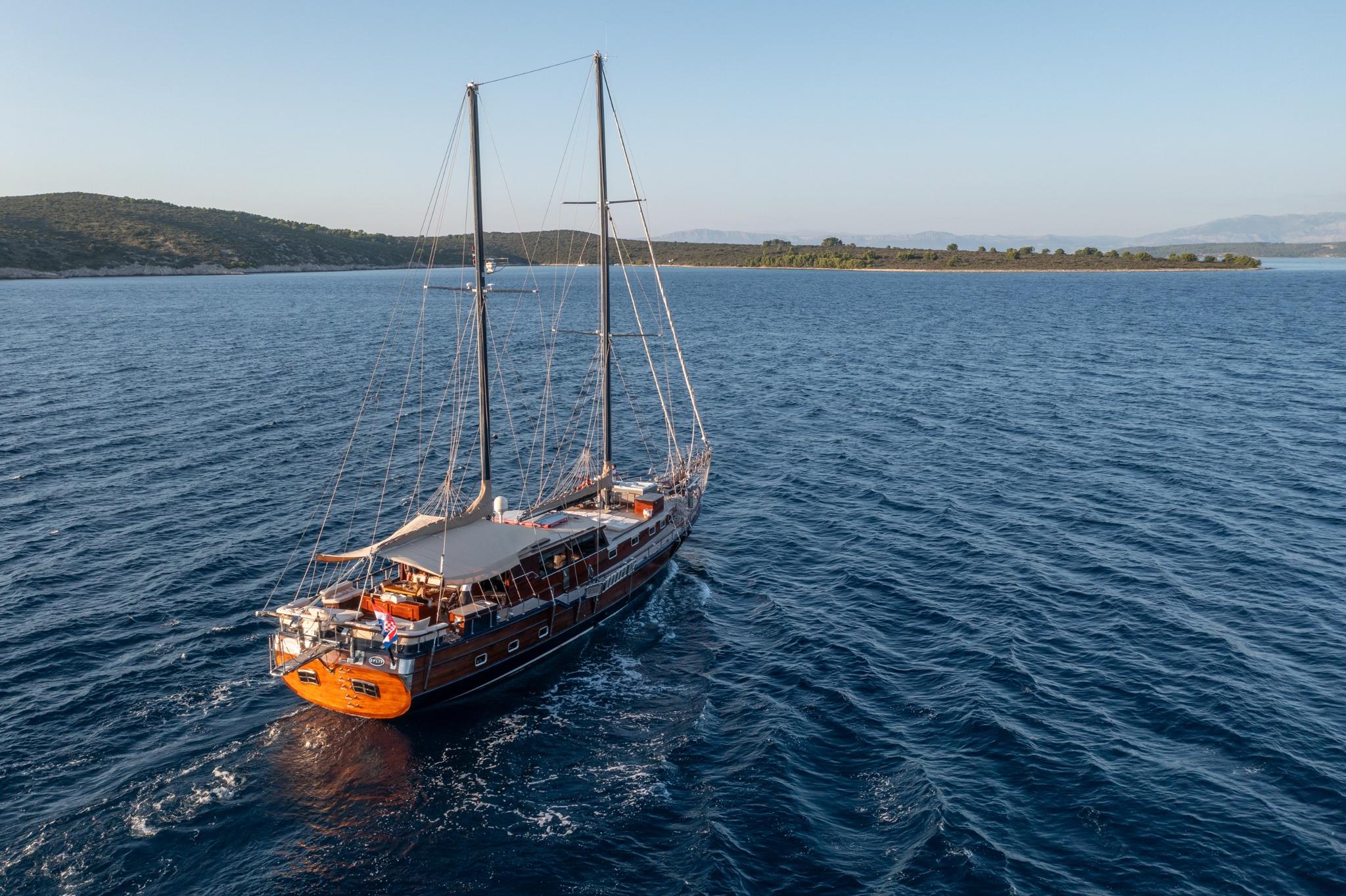 aerial view of traditional wooden gulet with two masts anchored in blue Mediterranean waters