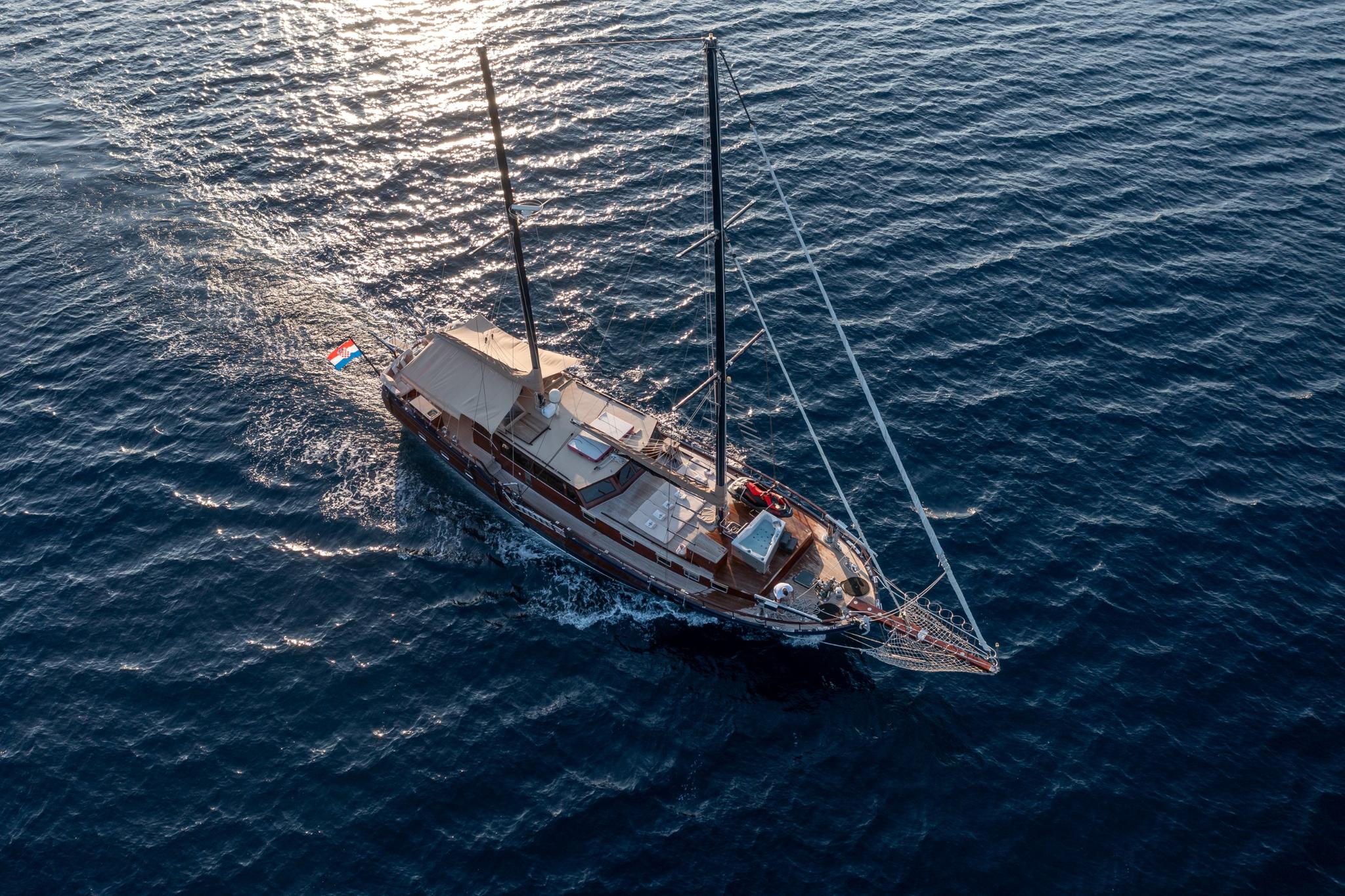 aerial drone view of traditional wooden gulet under sail on blue ocean waters