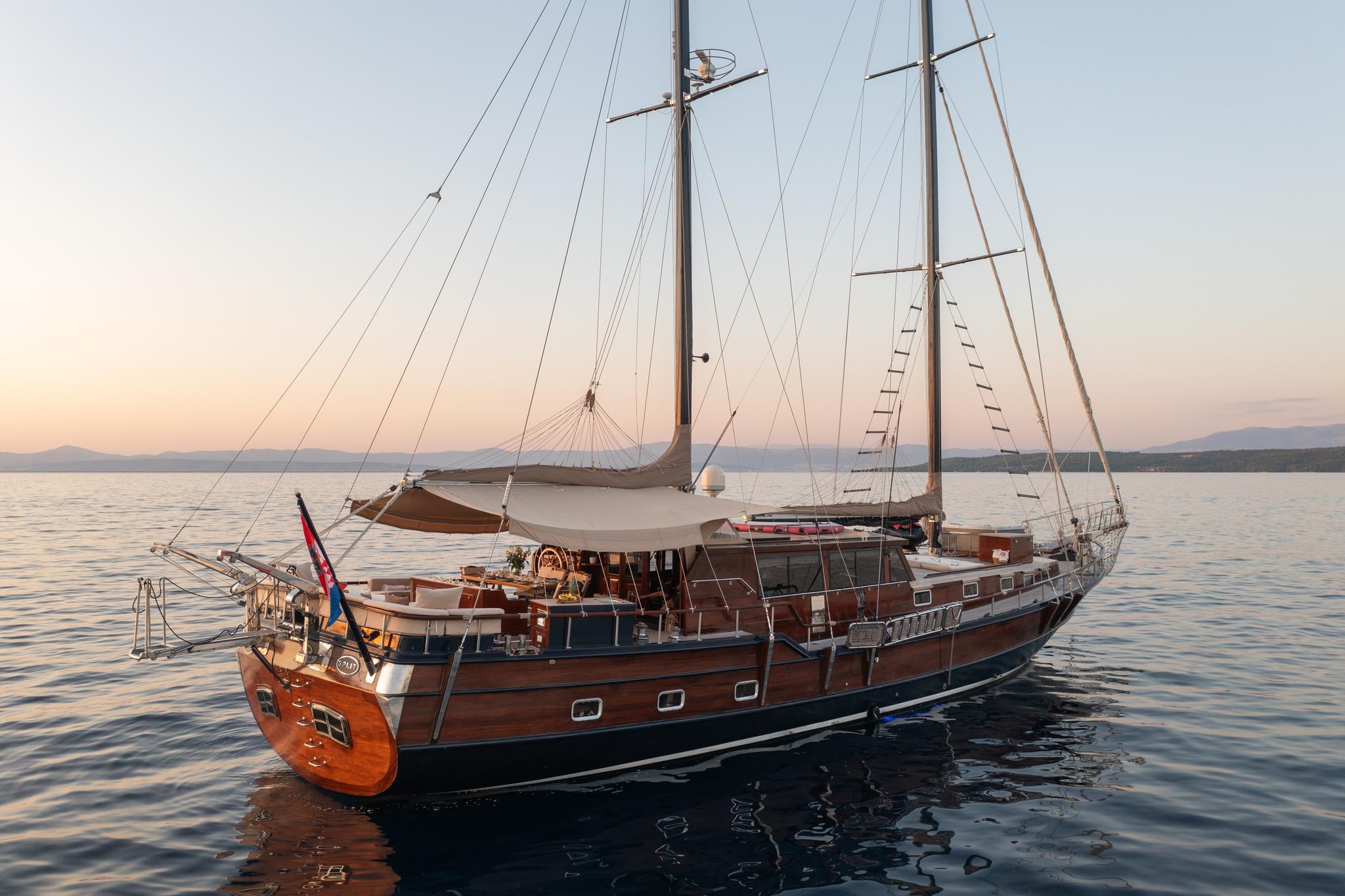 Classic wooden gulet with two masts anchored in calm waters at sunset