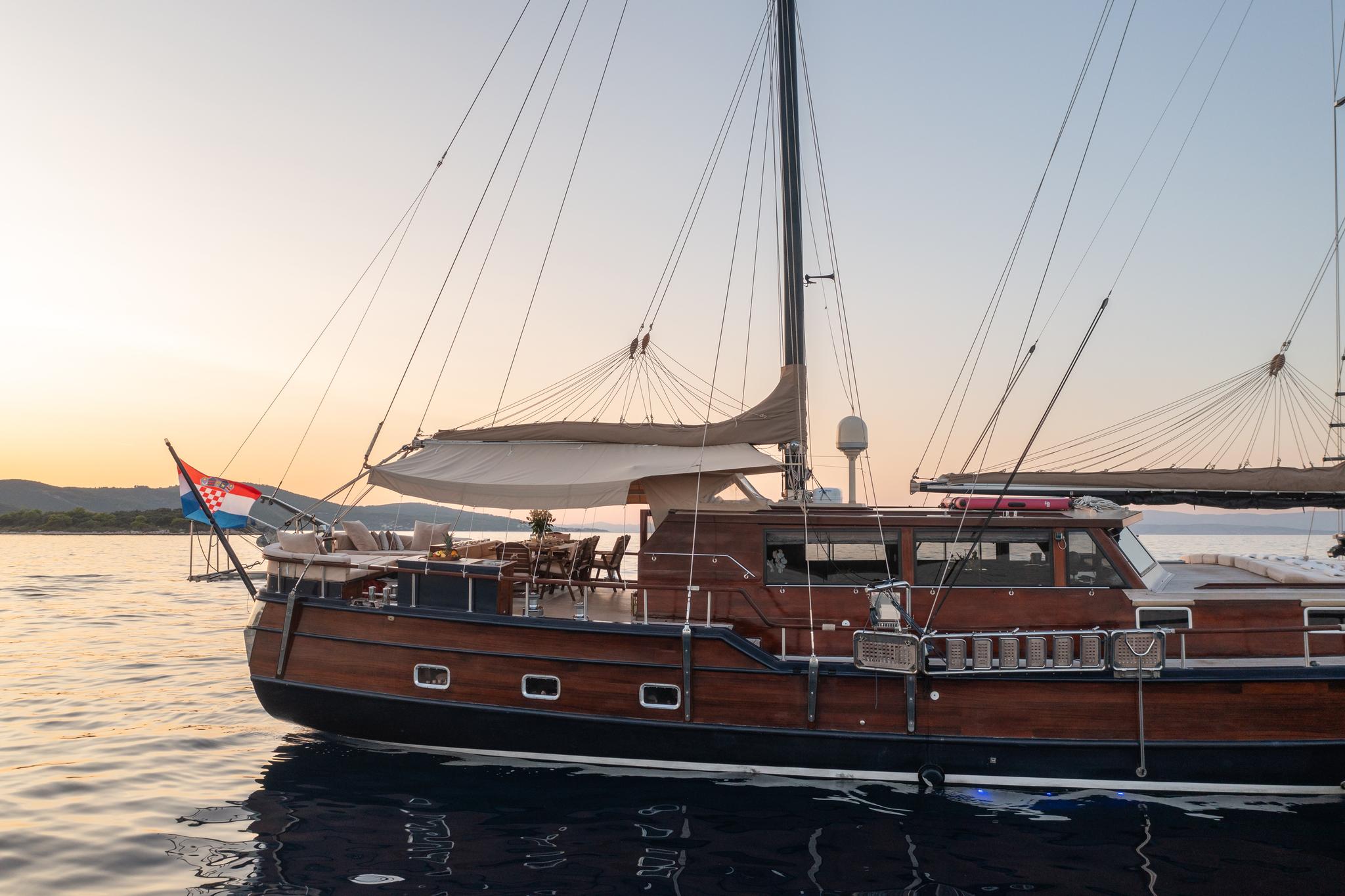 wooden gulet with Croatian flag anchored at sunset with rigging visible