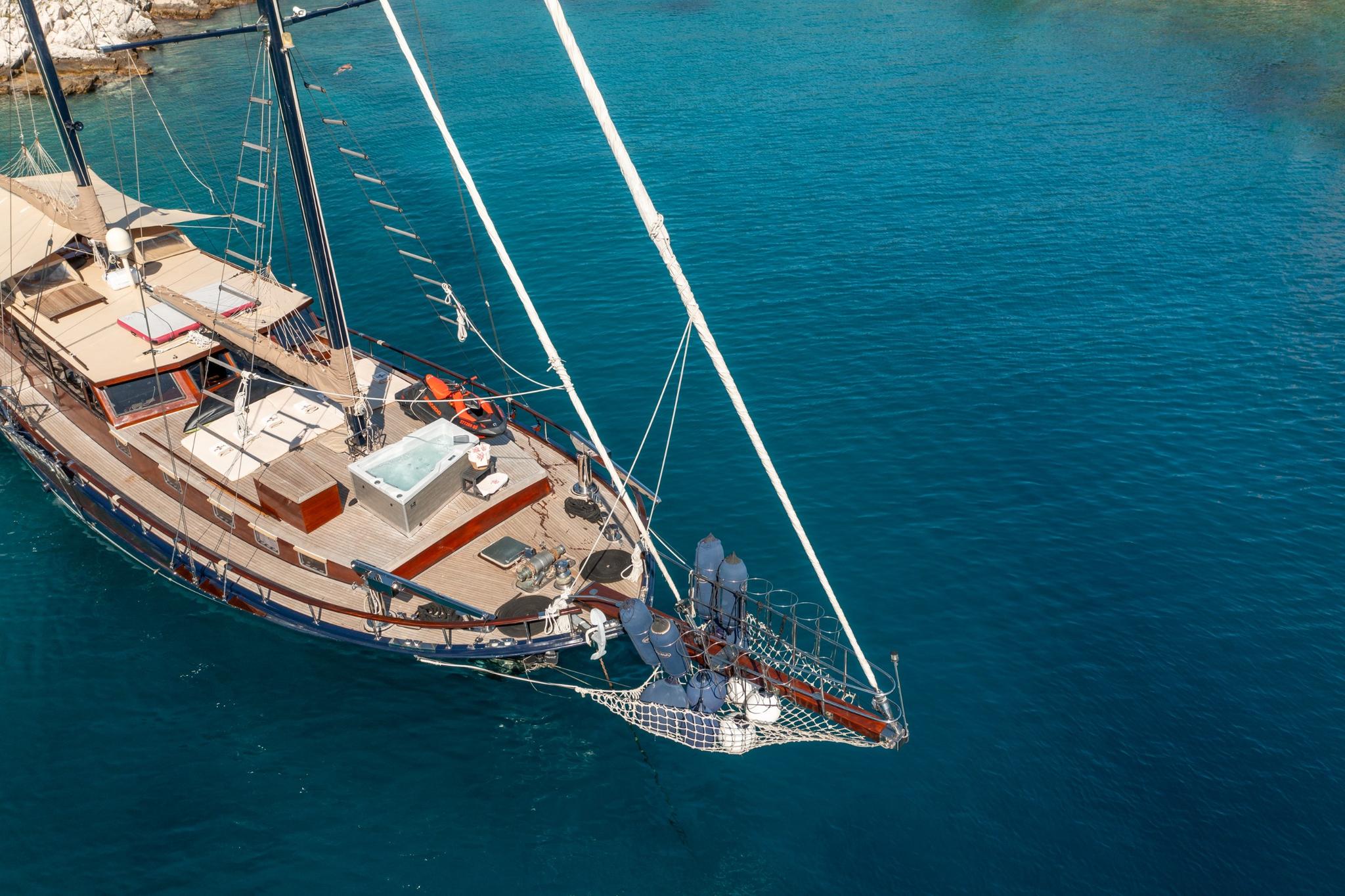 aerial view of traditional gulet yacht with jacuzzi anchored in crystal clear turquoise bay