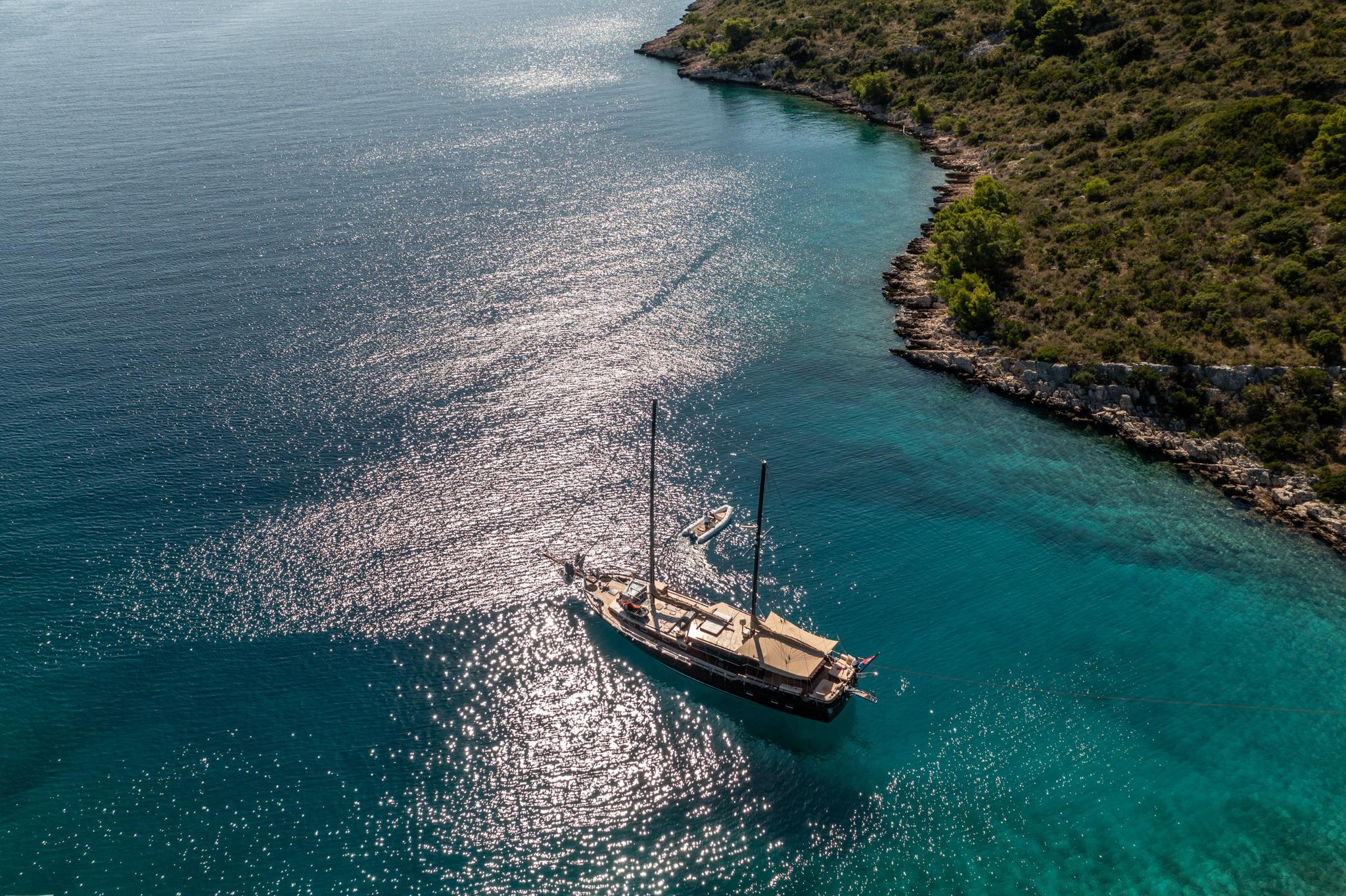 aerial view of traditional gulet yacht anchored in crystal clear turquoise Mediterranean bay