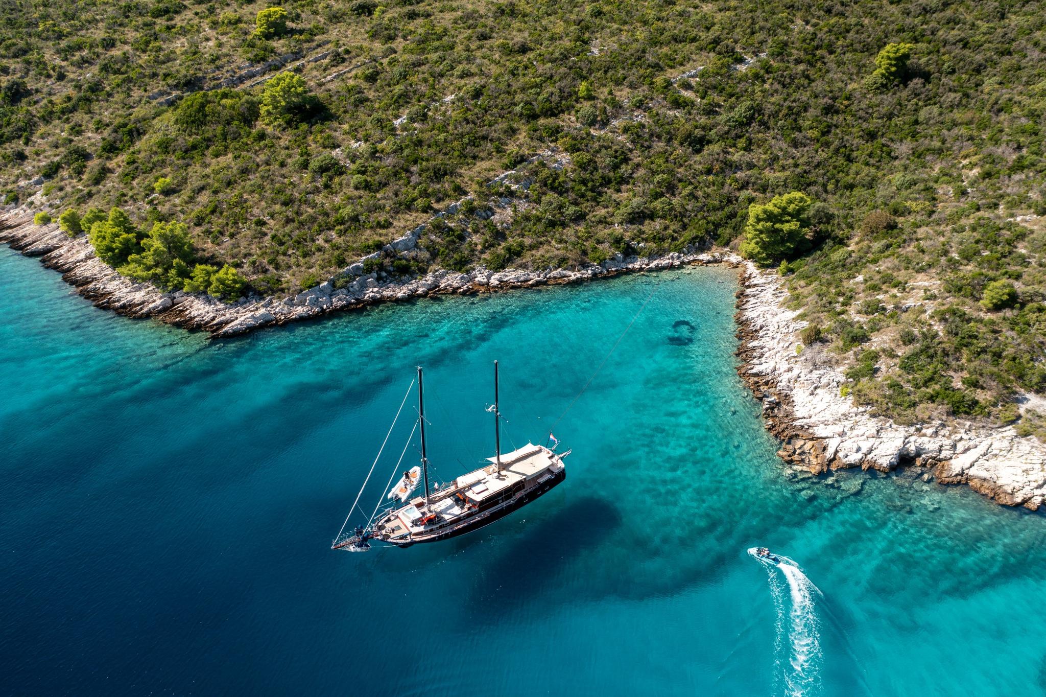 aerial view of traditional gulet yacht anchored in crystal clear turquoise Mediterranean bay