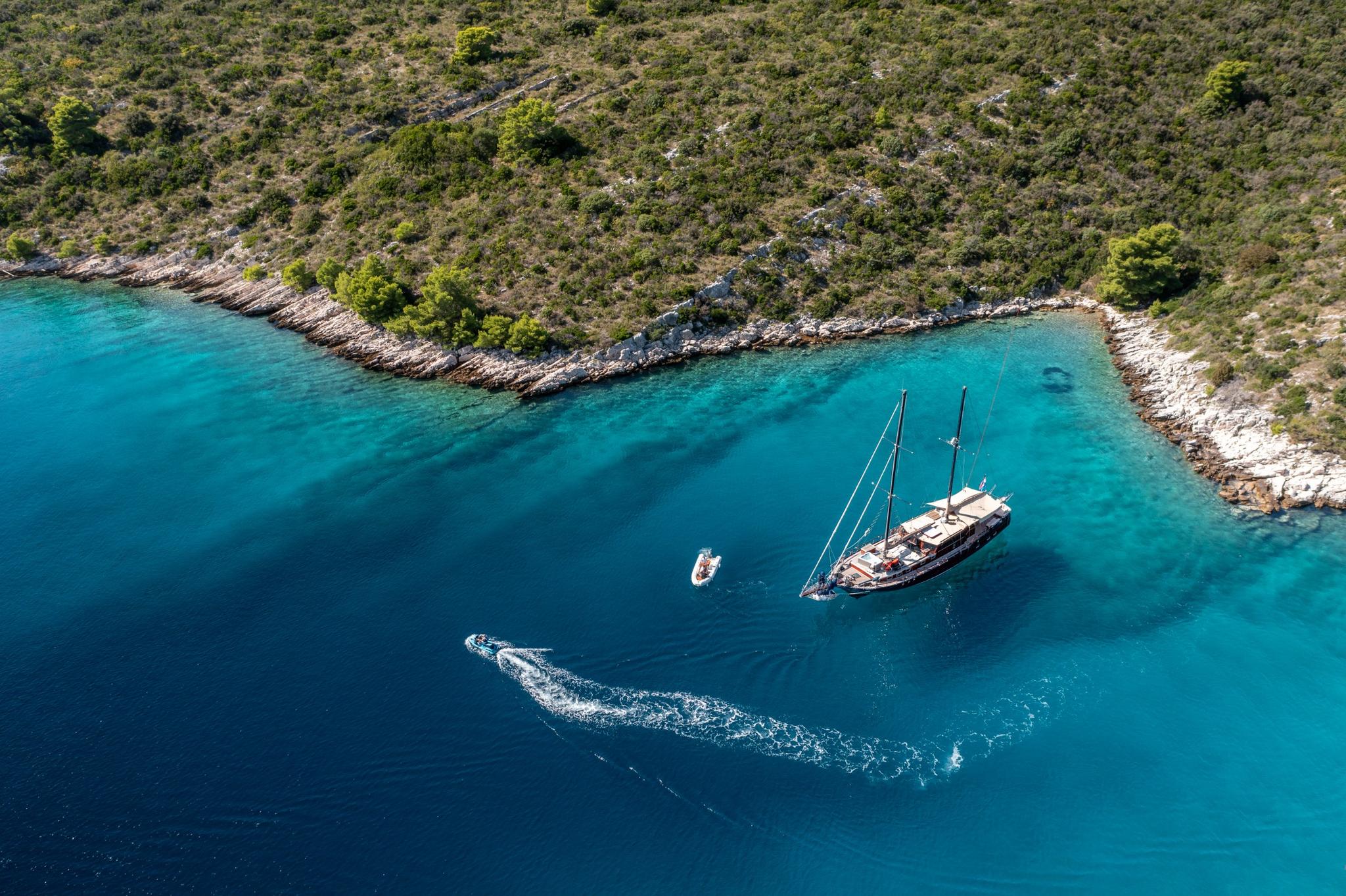 aerial view of traditional gulet yacht anchored in pristine turquoise Mediterranean bay