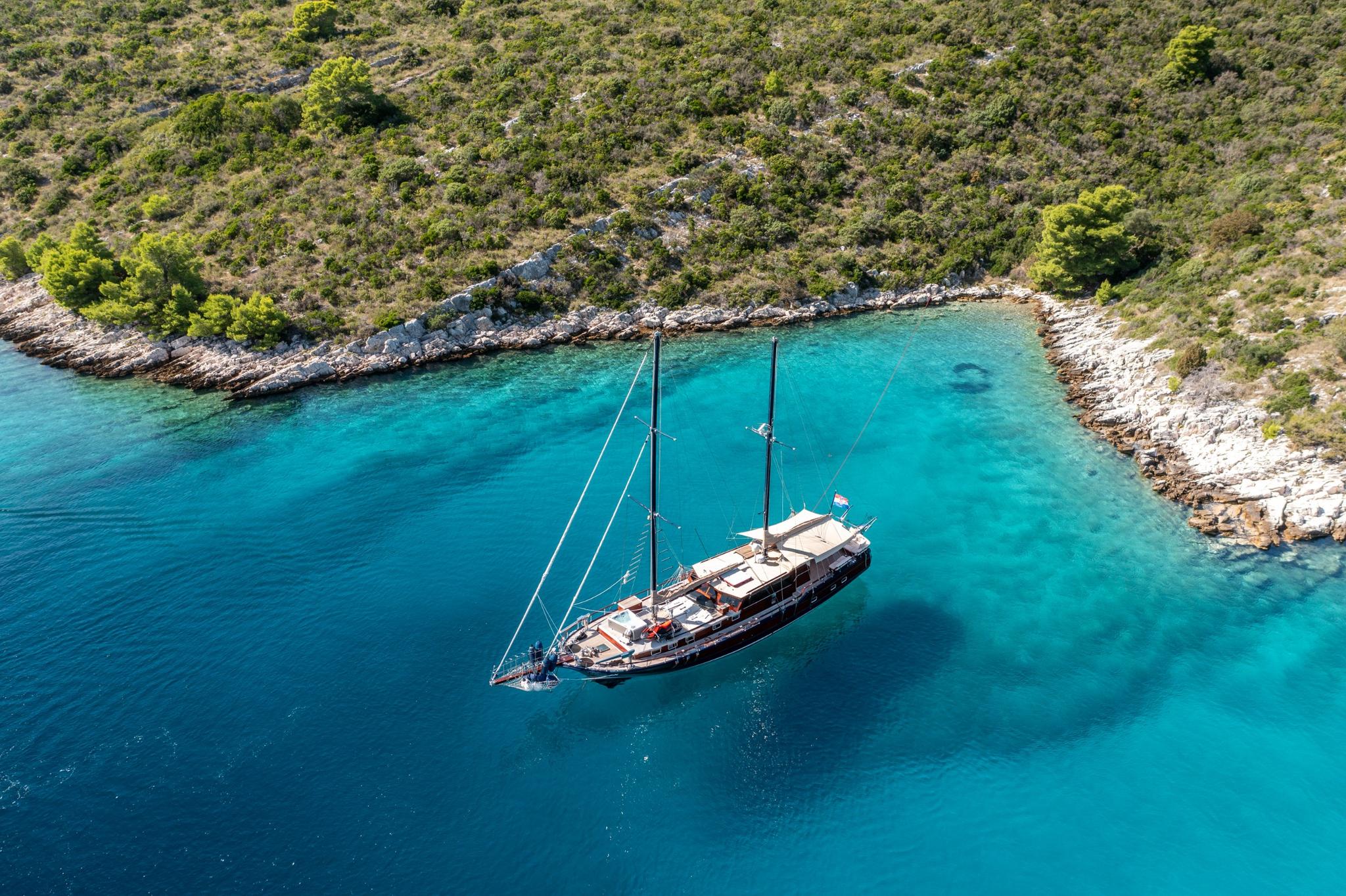Aerial view of traditional wooden gulet yacht anchored in pristine turquoise Mediterranean bay
