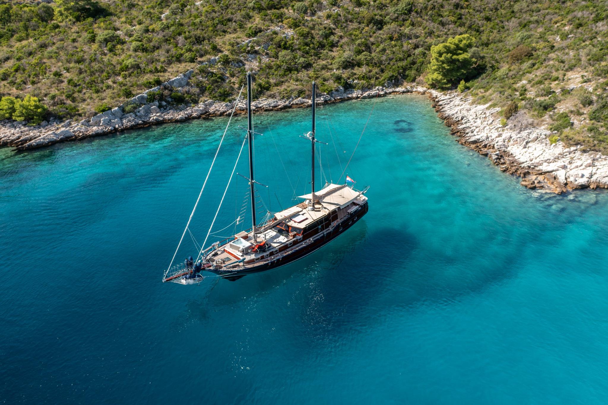 aerial view of traditional wooden gulet yacht anchored in secluded turquoise bay